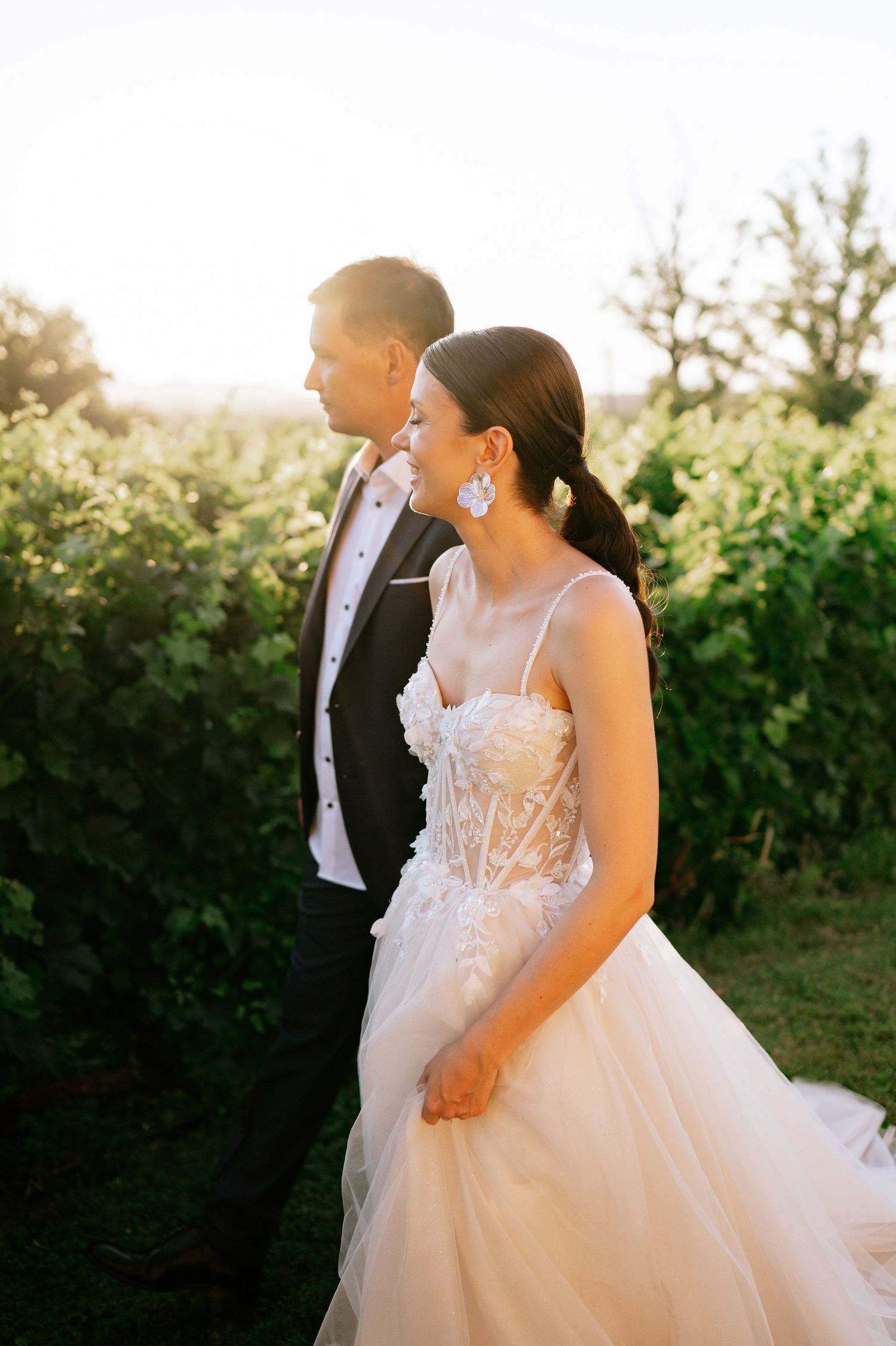 Wedding couple photographed in warm sunset light among garden greenery.