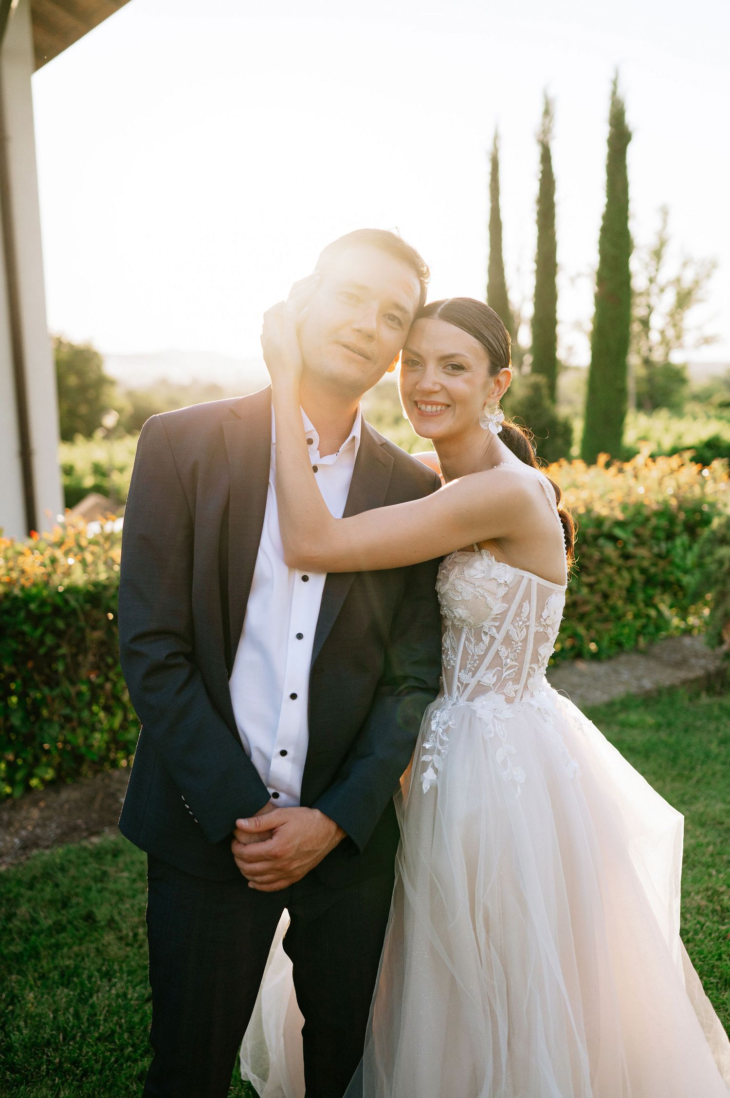Joyful wedding couple dancing in garden during sunset photo session.