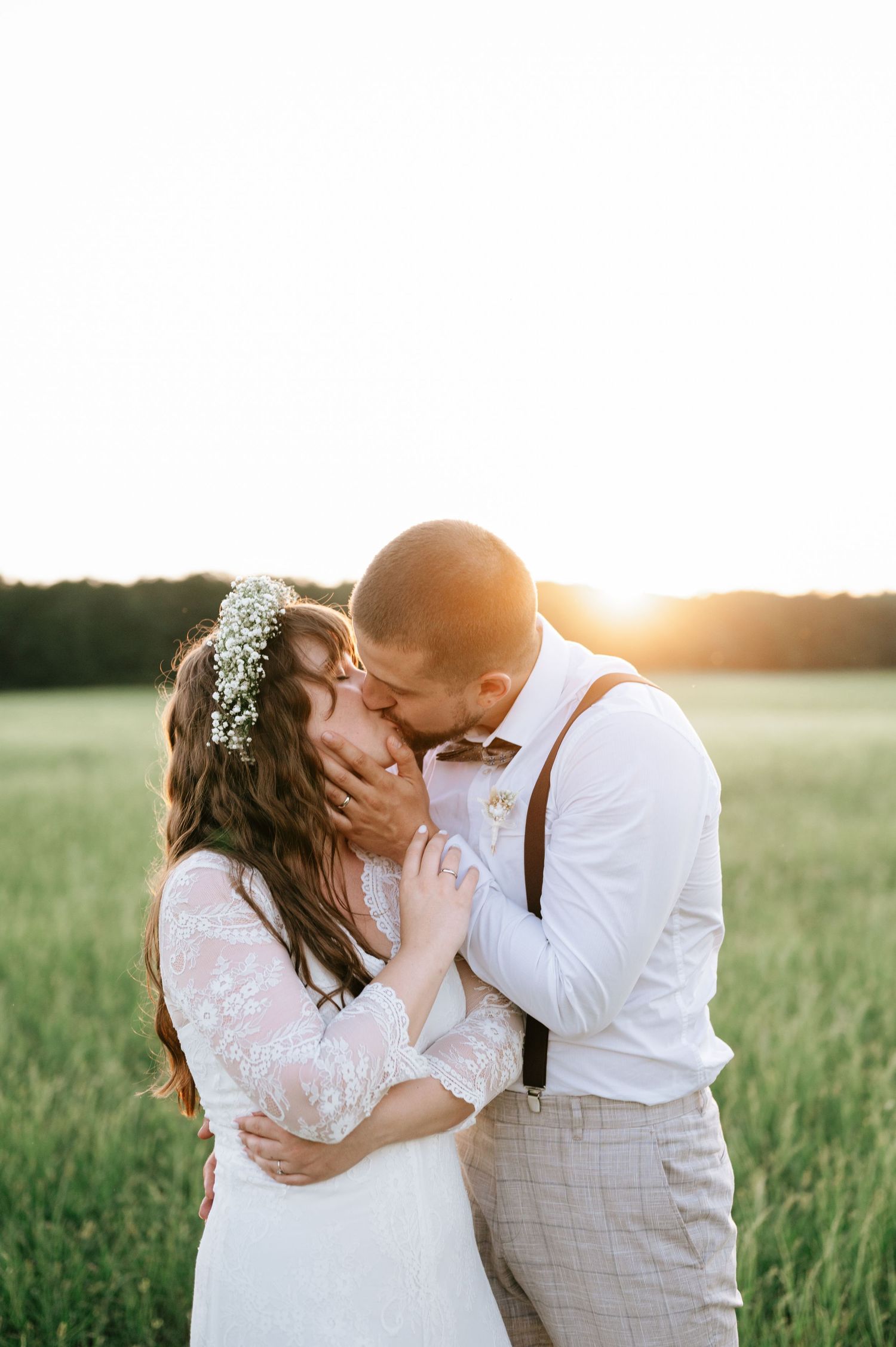Sunset wedding photos in a field show tender moments between newlyweds.