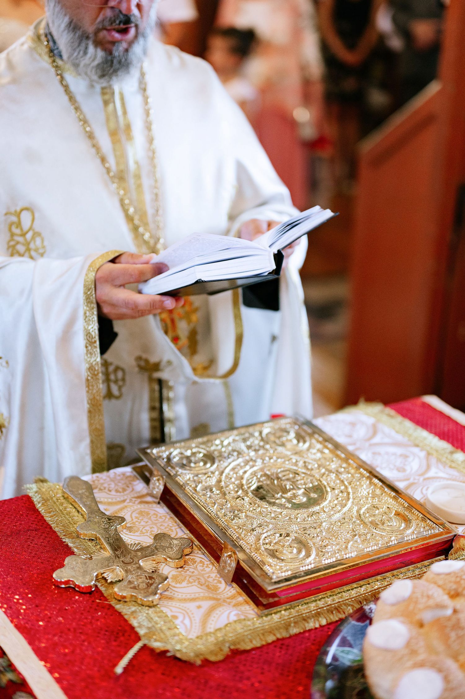 Close-up of ornate gold religious books and ceremonial items on red altar cloth.
