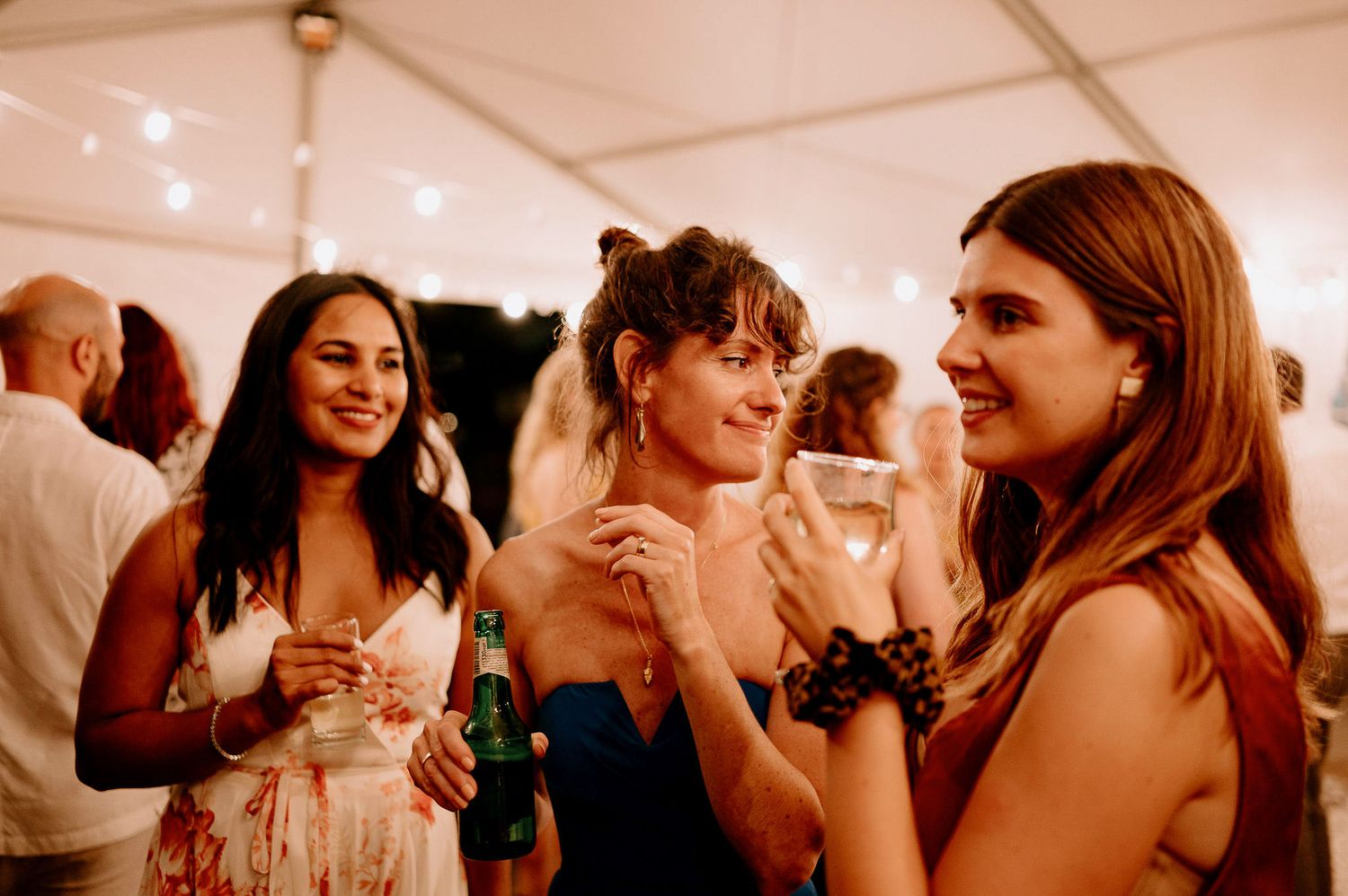 Guests laugh and smile during emotional moments at a wedding reception.