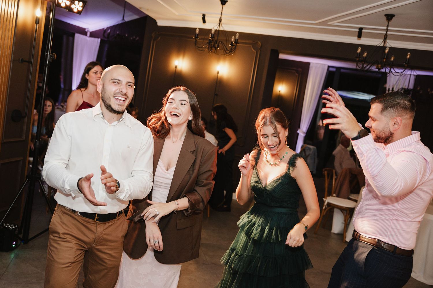 Wedding guests dancing and having fun at an indoor reception party.