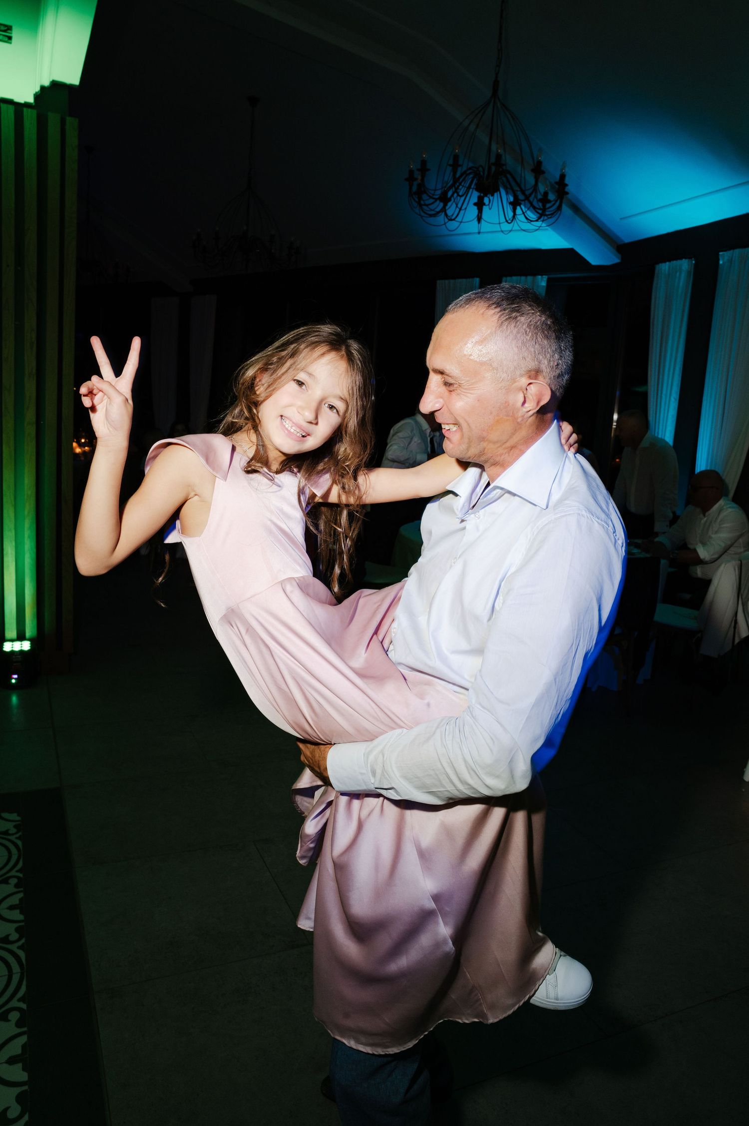 Guests dancing at a wedding reception under dramatic blue and green lighting.