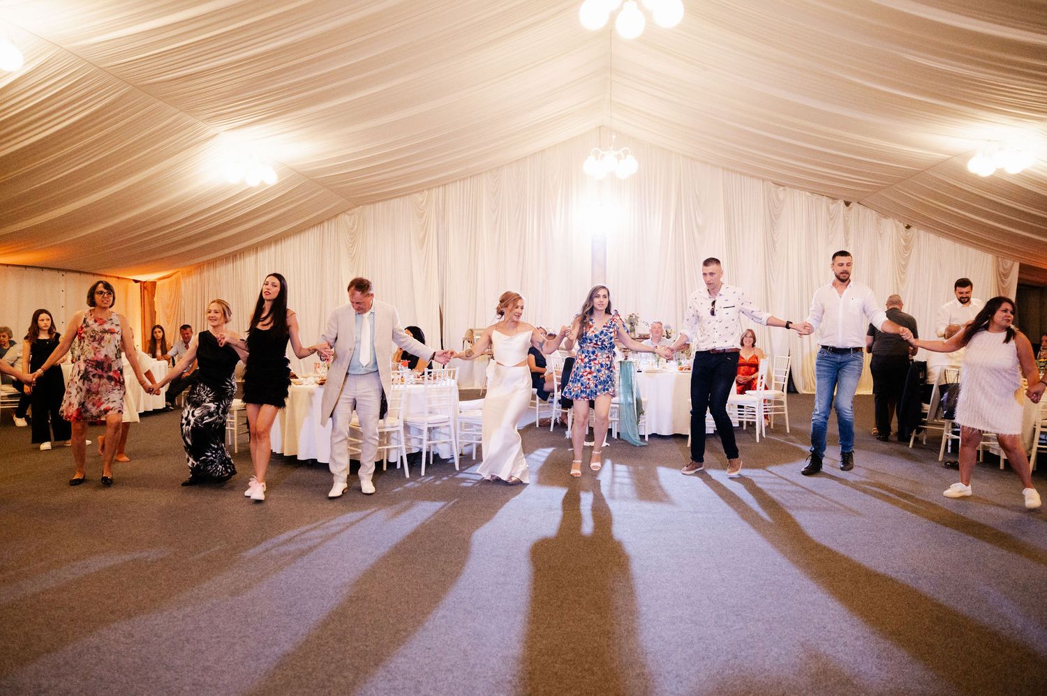 A sequence of dance floor scenes at a wedding reception showing people dancing and celebrating under a white tent.