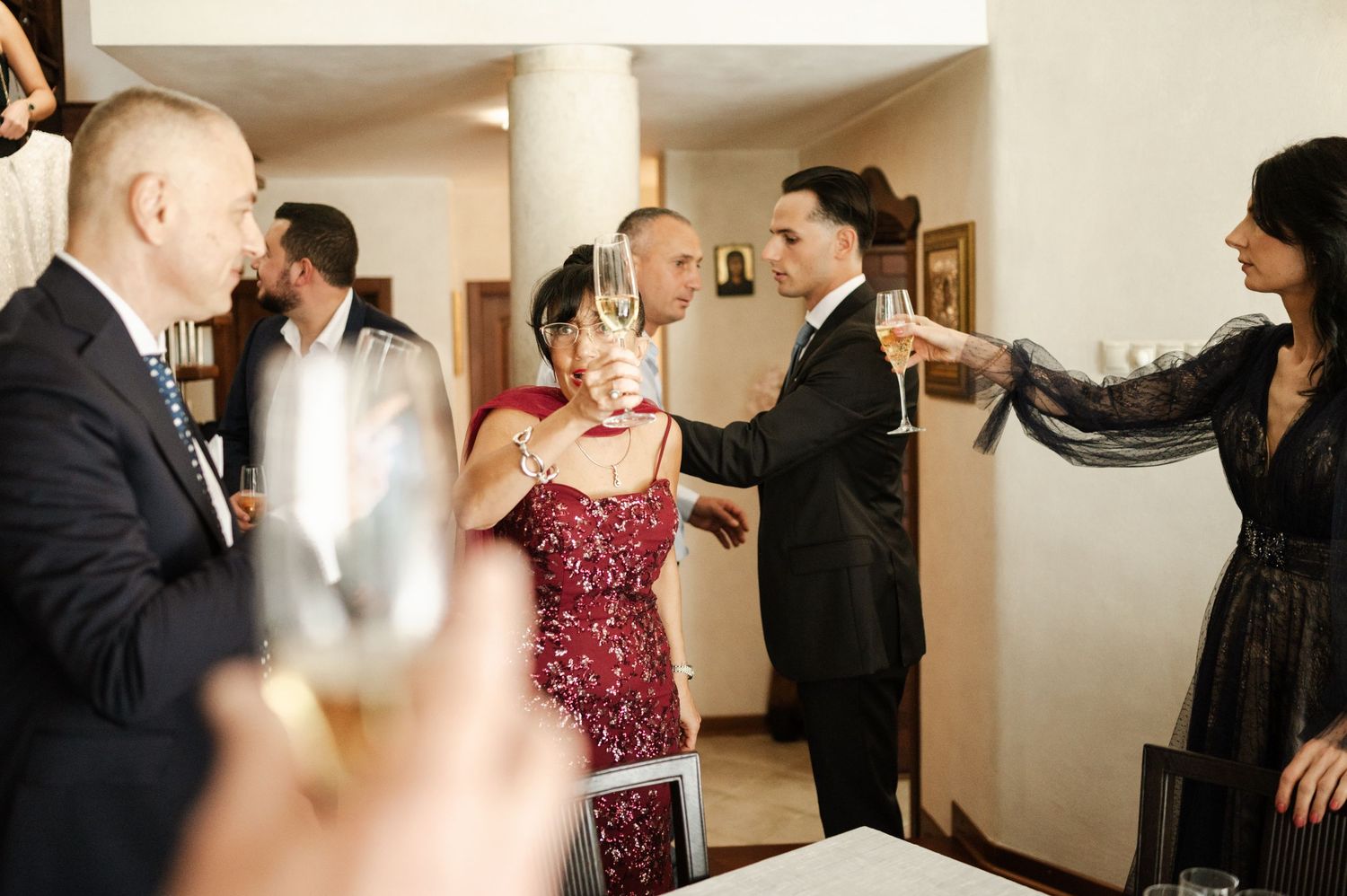 Wedding guests mingle and celebrate with champagne at an indoor reception.