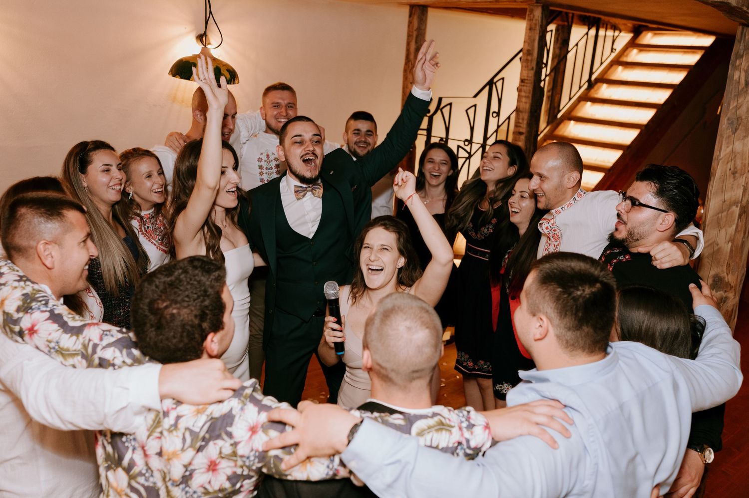 Panoramic view of wedding celebration showing guests dancing and interacting in reception hall.