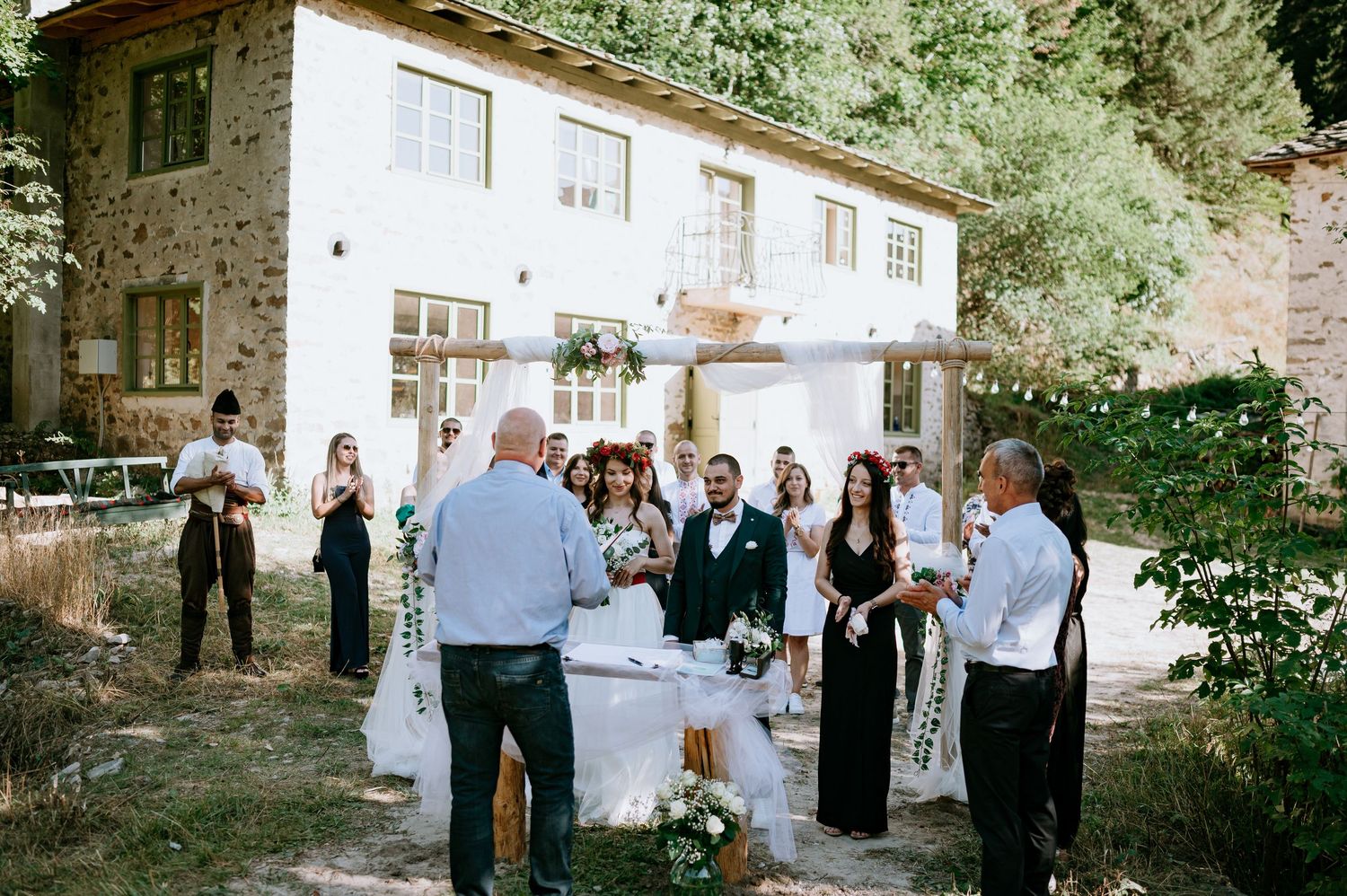 Guests enjoying outdoor wedding festivities at stone villa with white decor.