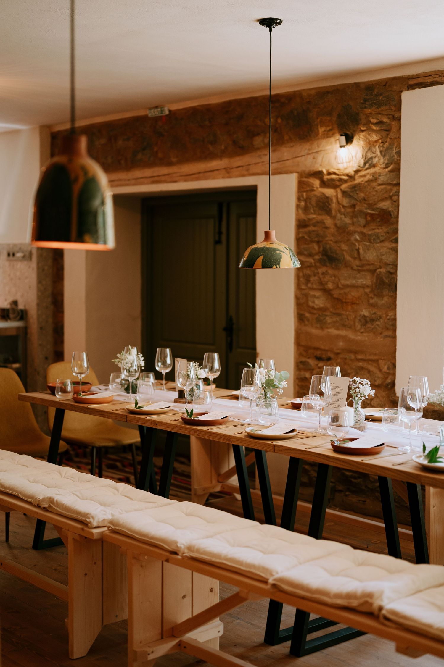 Modern rustic dining space with minimalist wooden tables and industrial-style lighting.