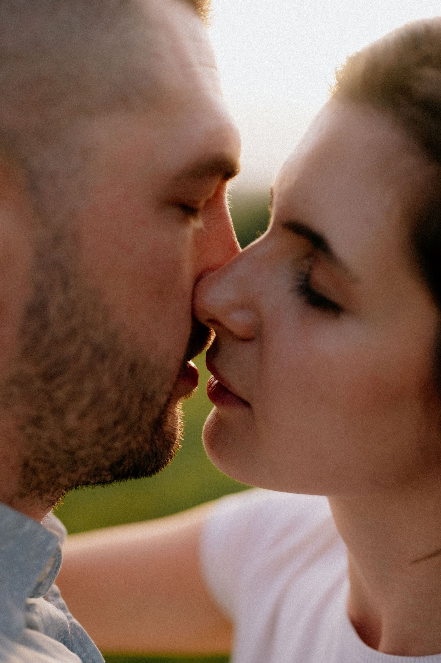 Romantic couple sharing an intimate close-up moment against natural lighting.