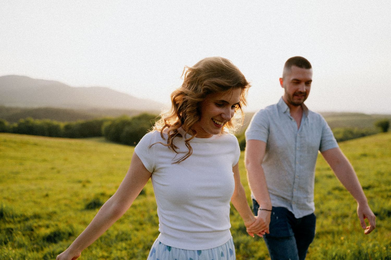 Joyful couple enjoying a carefree moment in a grassy meadow.