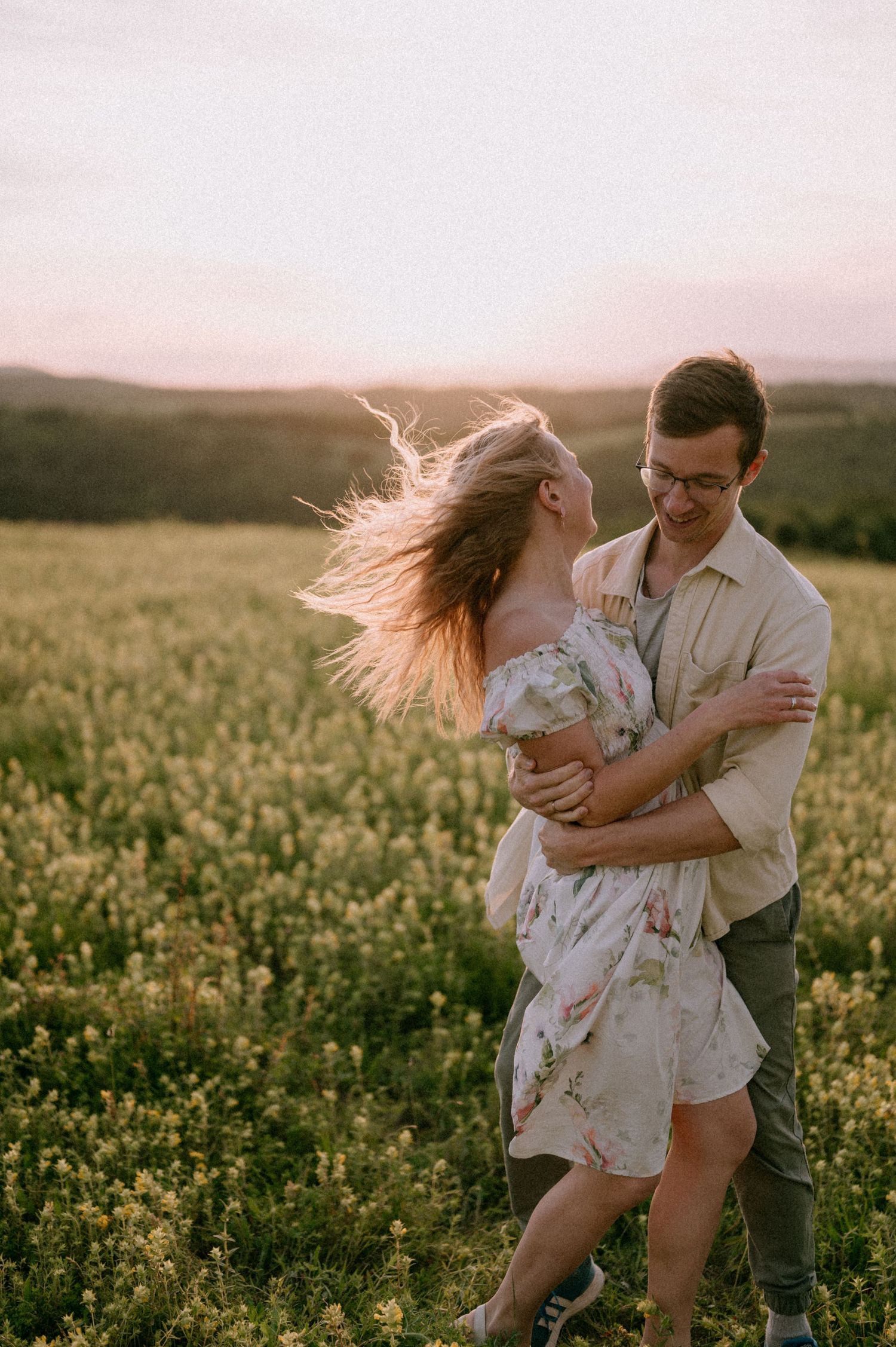A couple spins together in a wildflower meadow during golden hour.