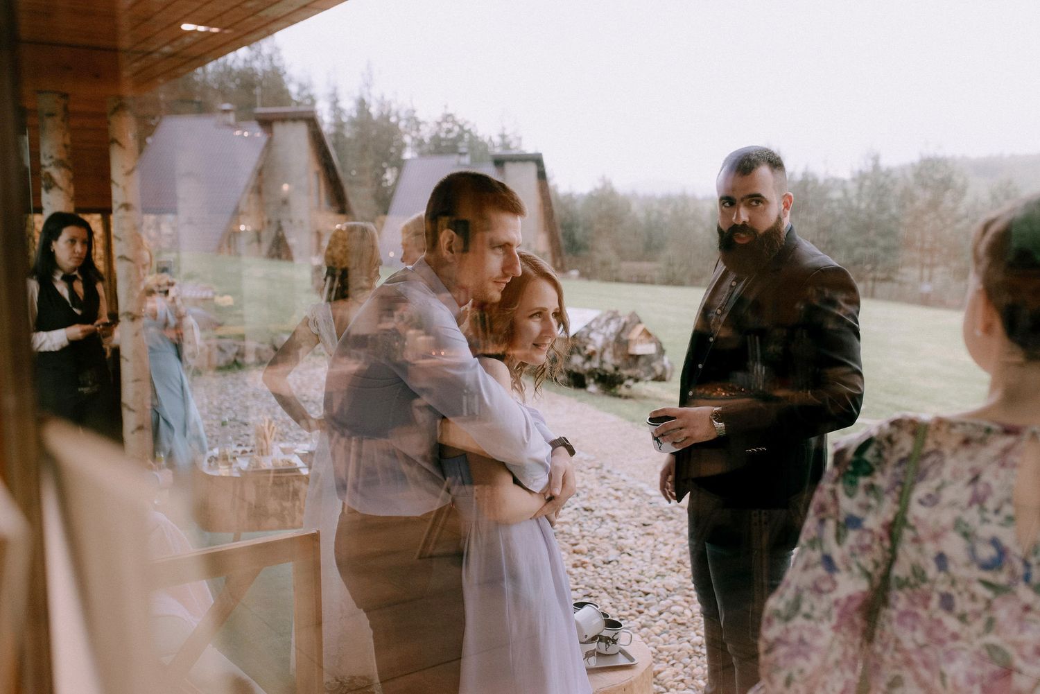 Wedding venue exterior with guests gathering under covered porch area.