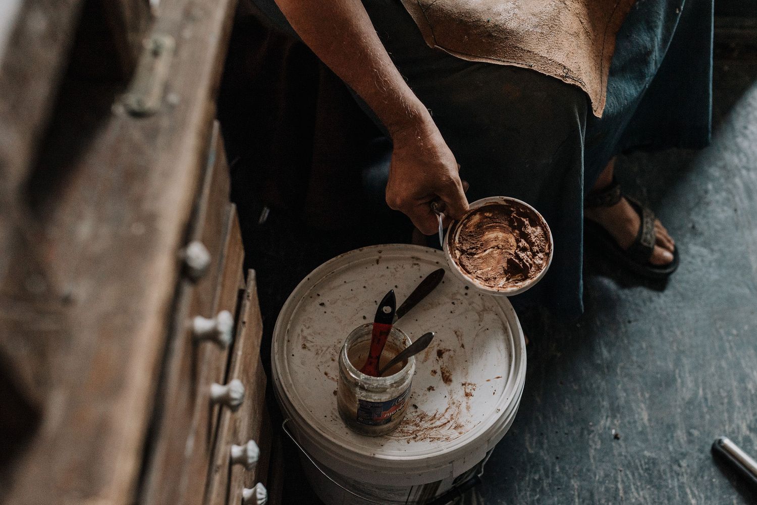 Hands work with clay or pottery materials in a dimly lit studio.
