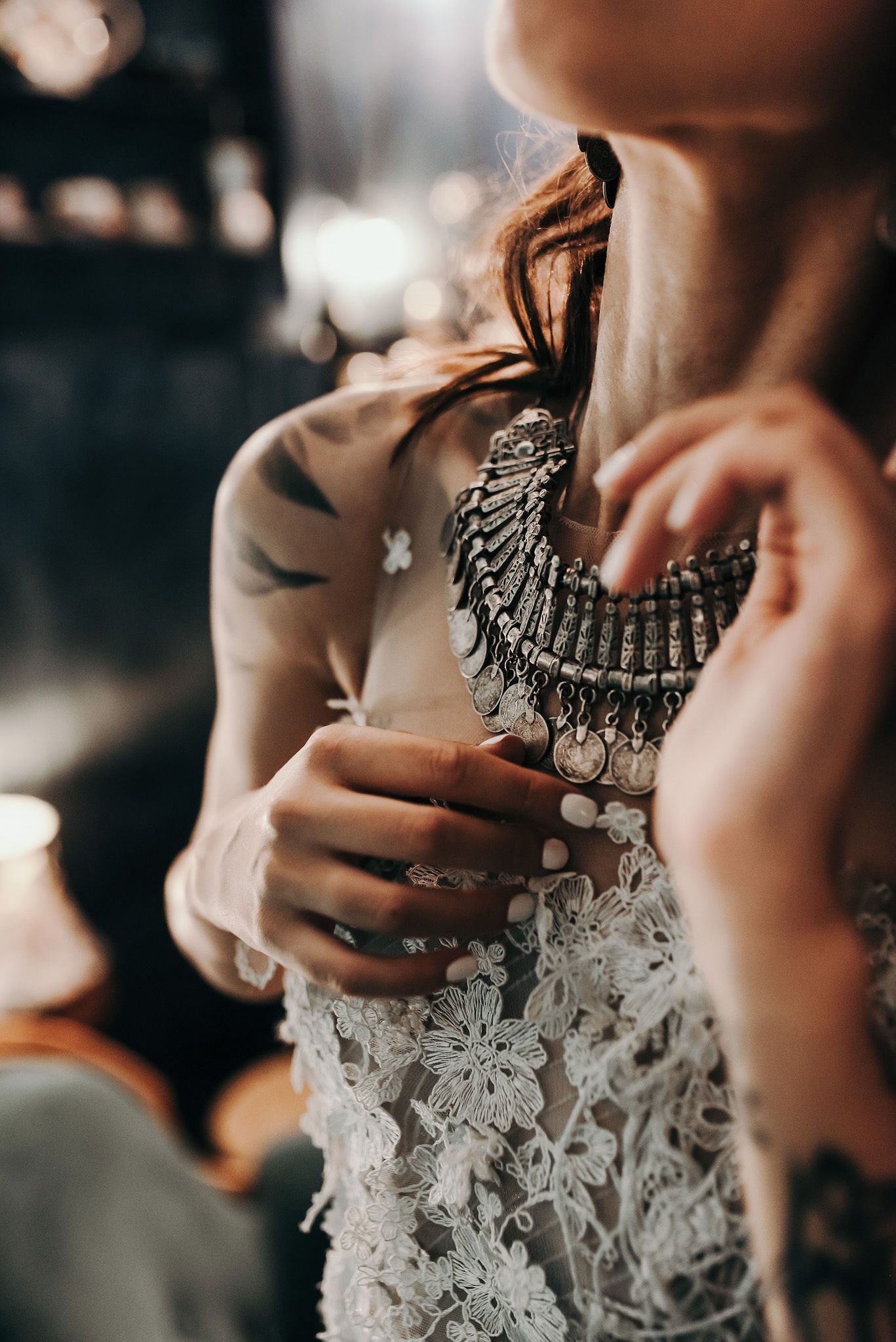 Close-up details of intricate lace and statement necklace in moody lighting.