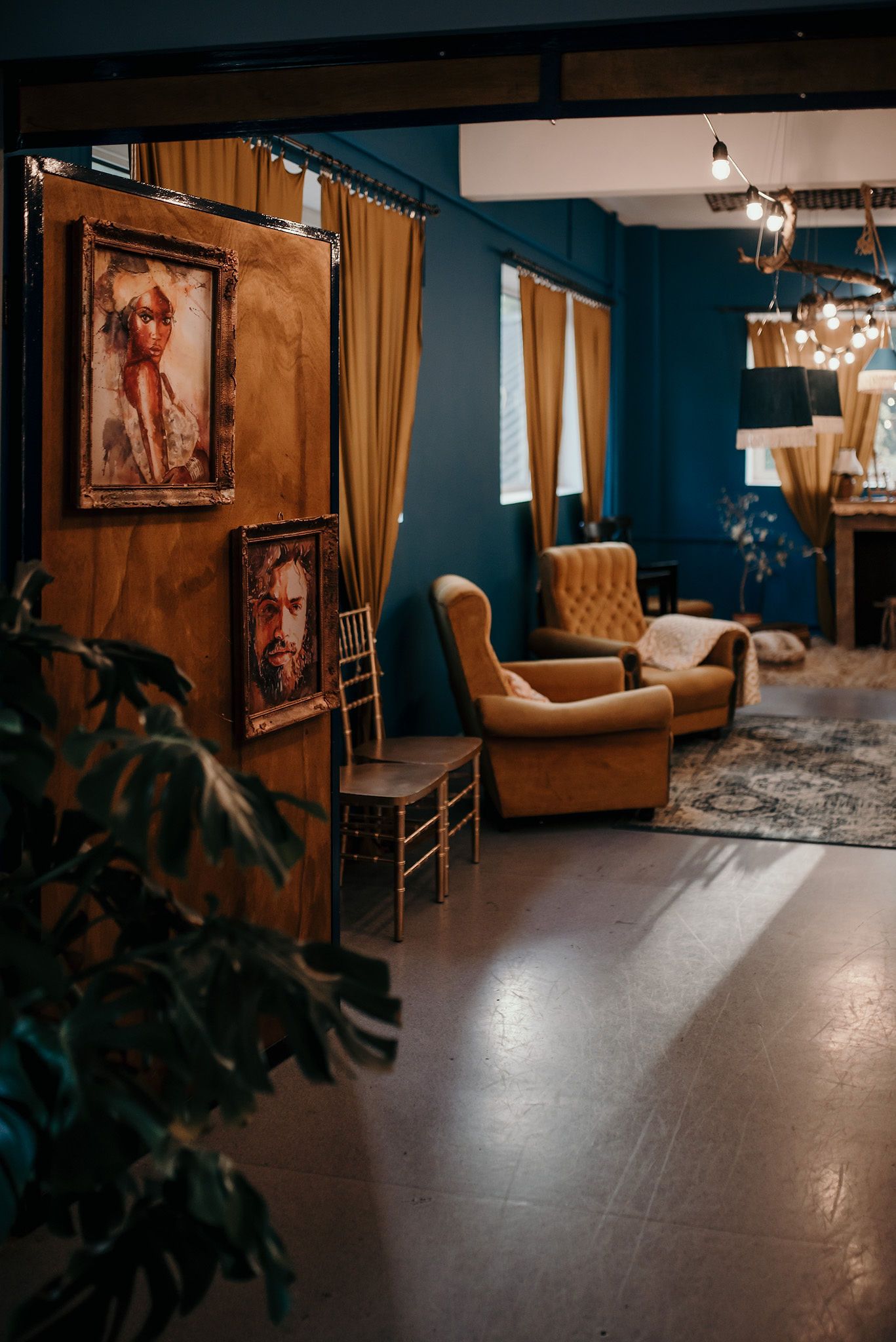Interior space with deep blue walls, gold curtains, and vintage furniture.