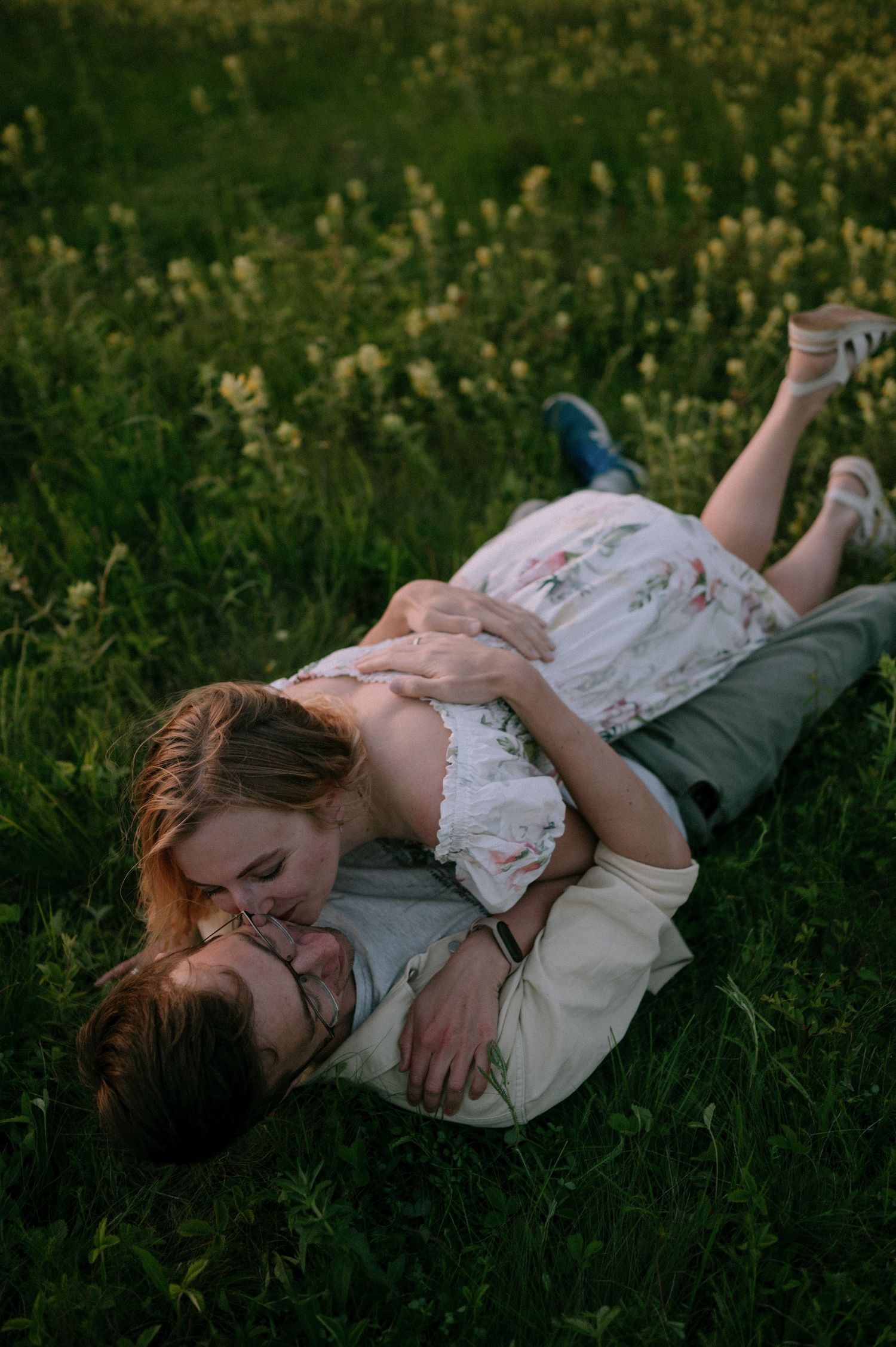 Two people share a tender moment while resting in a wildflower meadow.