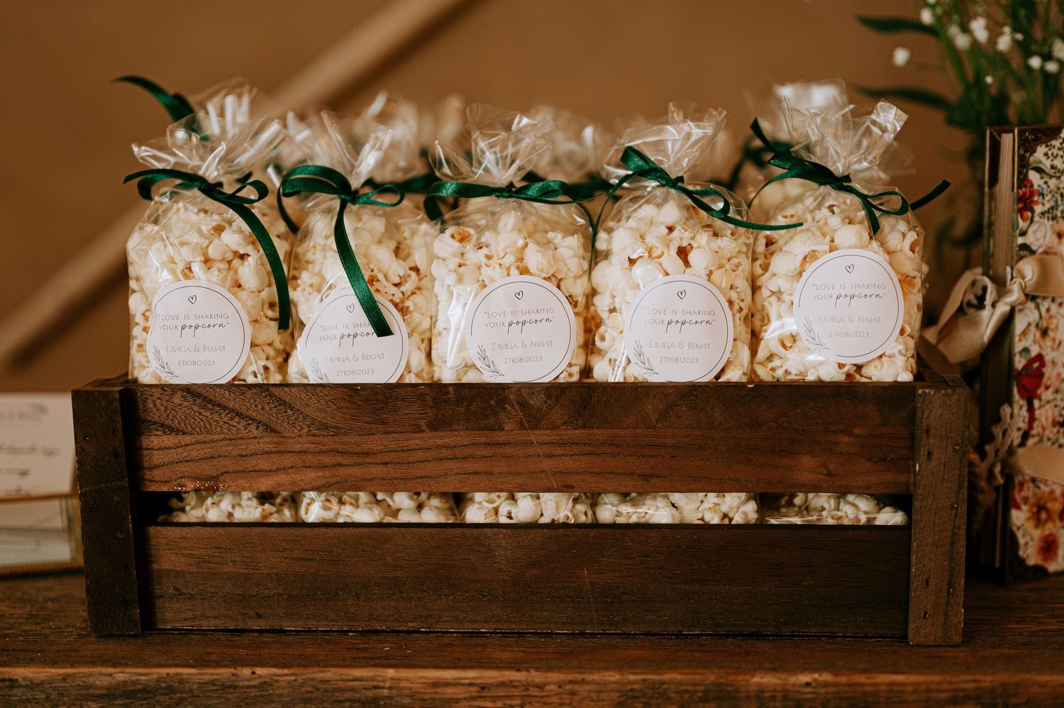 Wooden display shelf filled with small decorated favor boxes and white flowers.