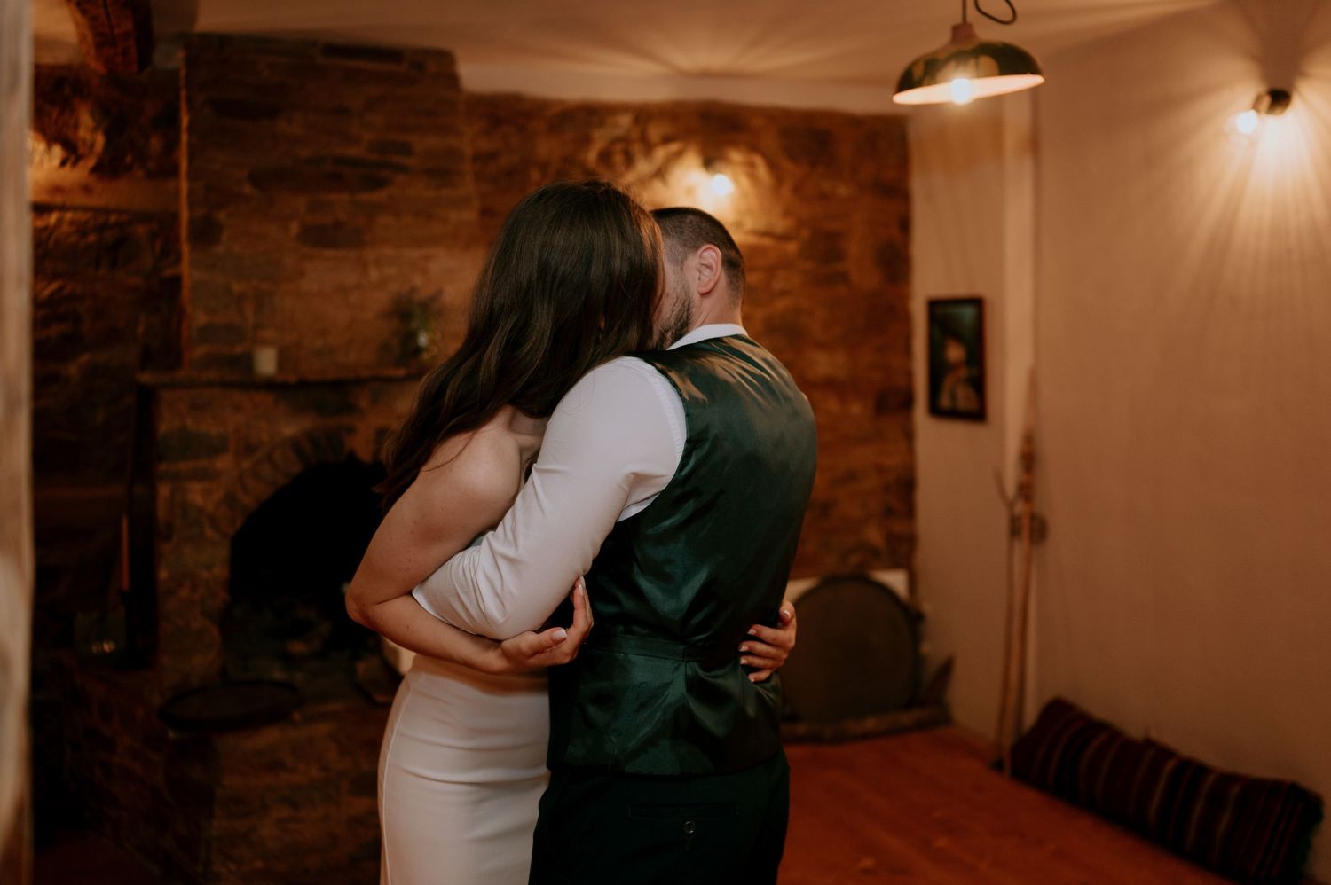 Couples dancing together in a warmly lit room with brick walls.