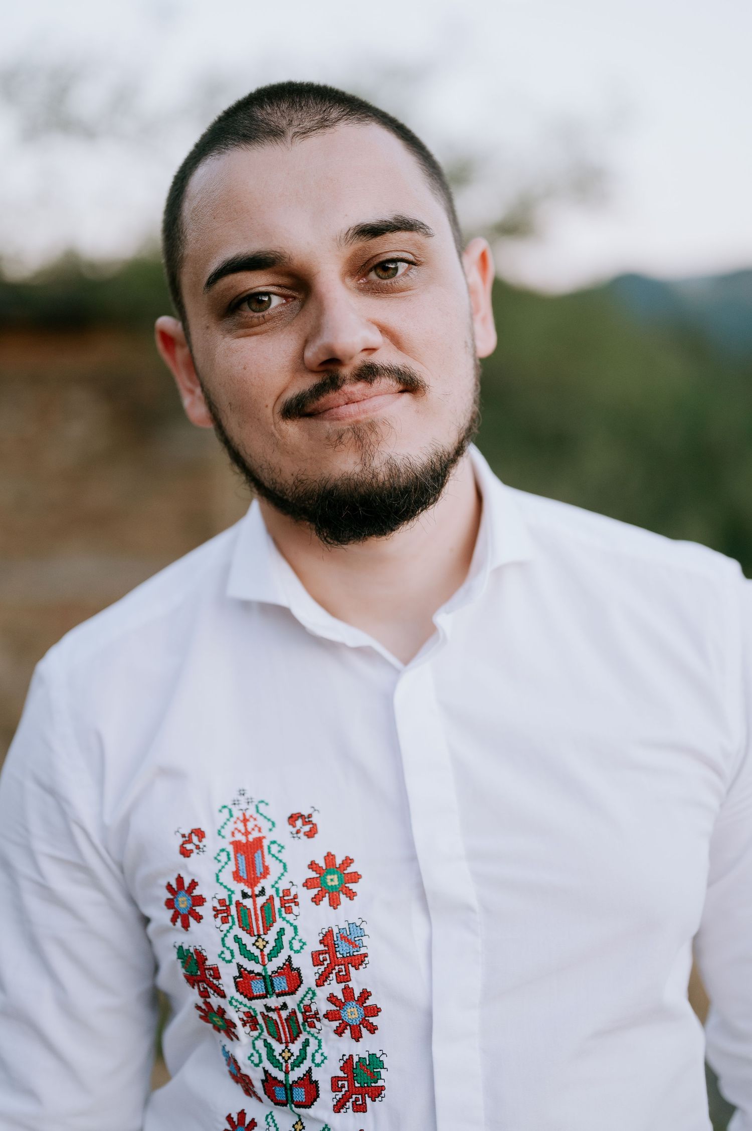 White dress shirt with traditional floral embroidery details shown in close-up shots.