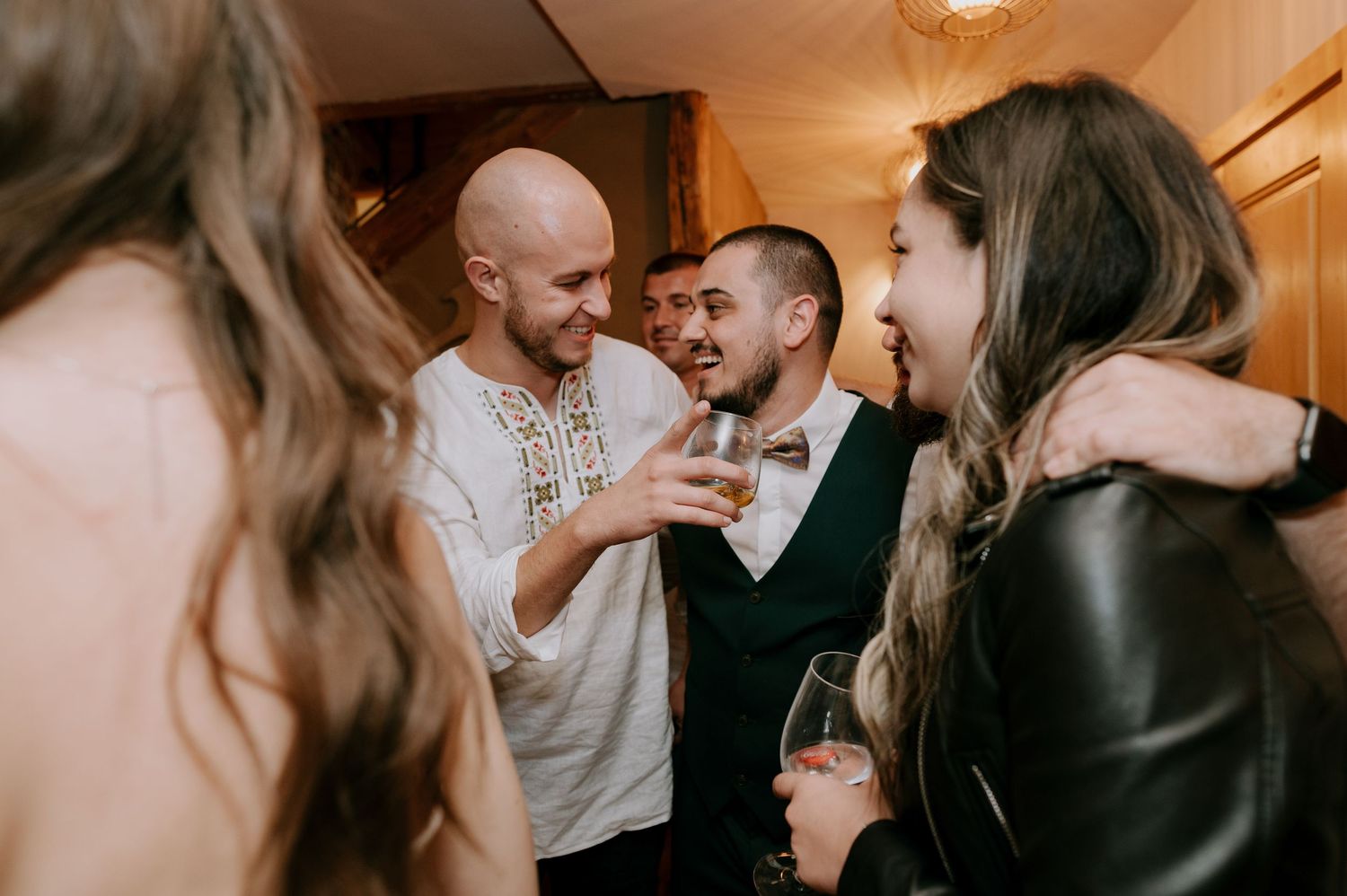 Party guests engaged in animated conversation at an indoor gathering.
