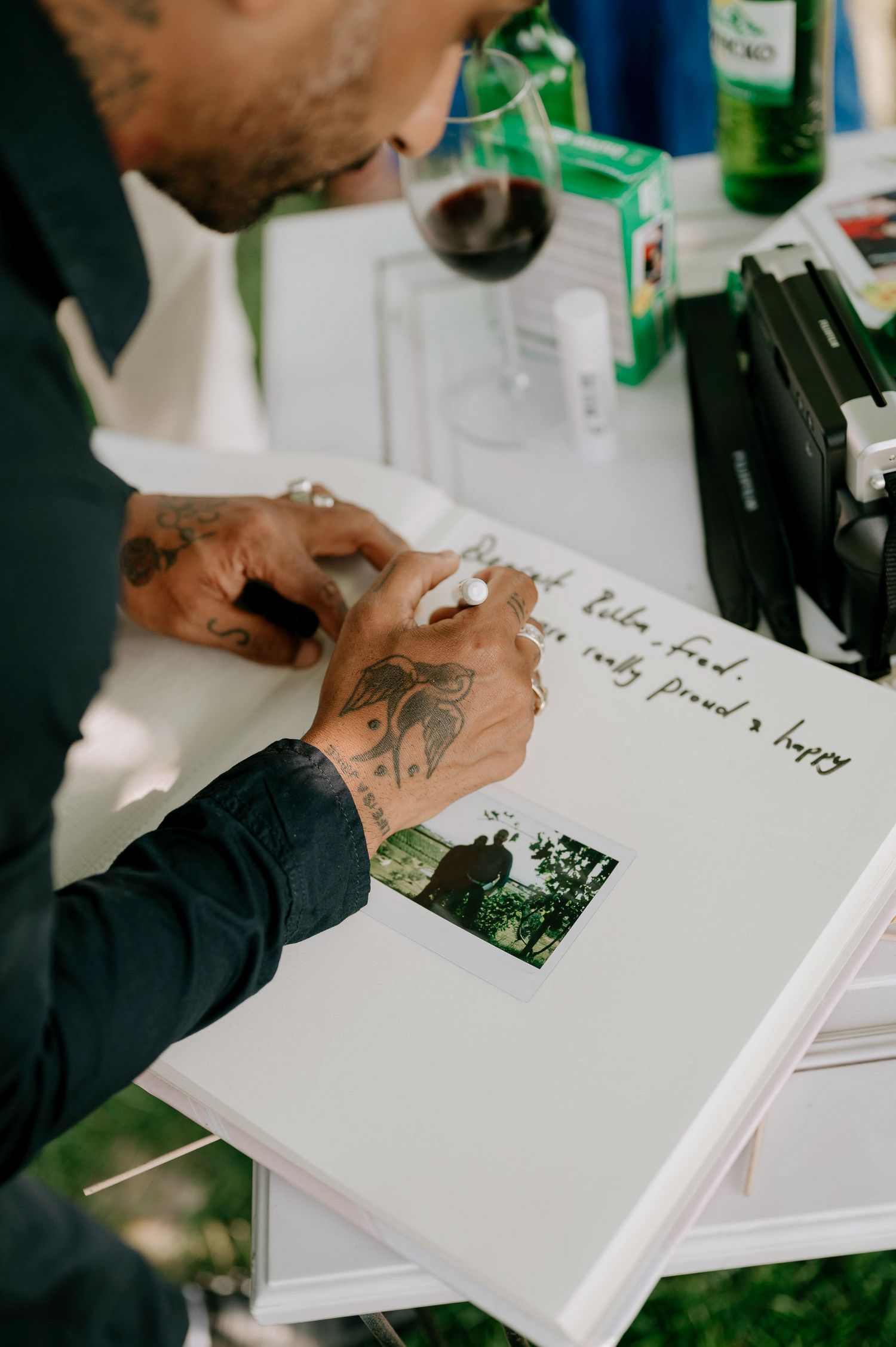 Hands writing in a white guest book or photo album with photographs being added to the pages.