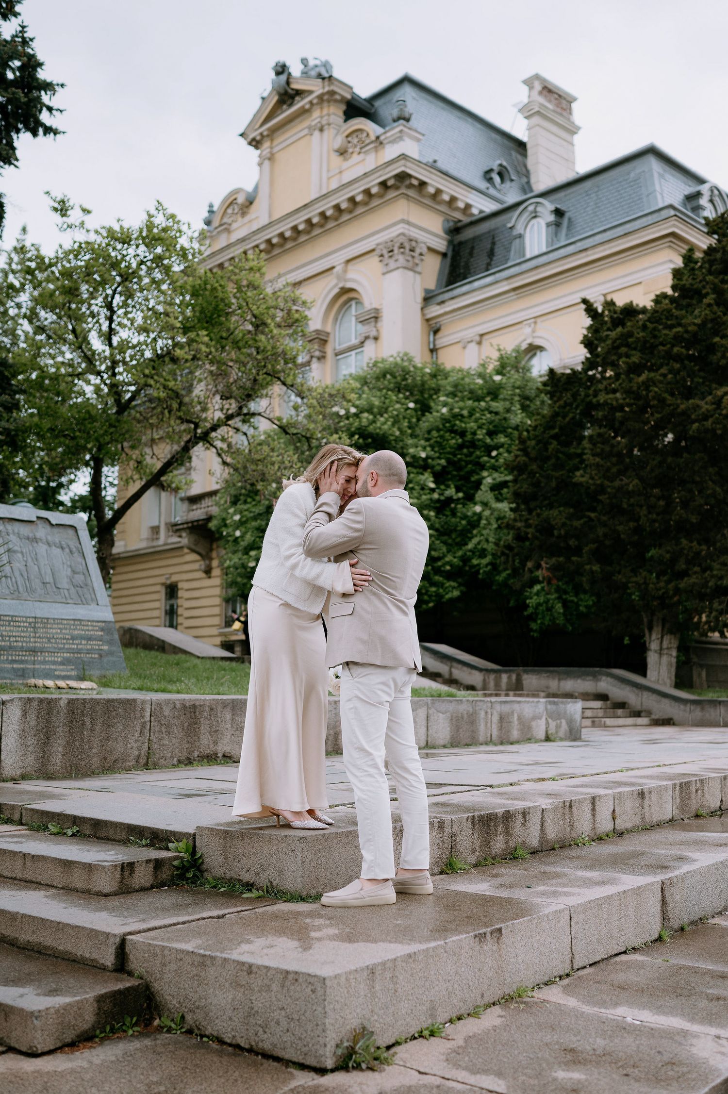Intimate moment captured between two people in white on historic building steps.
