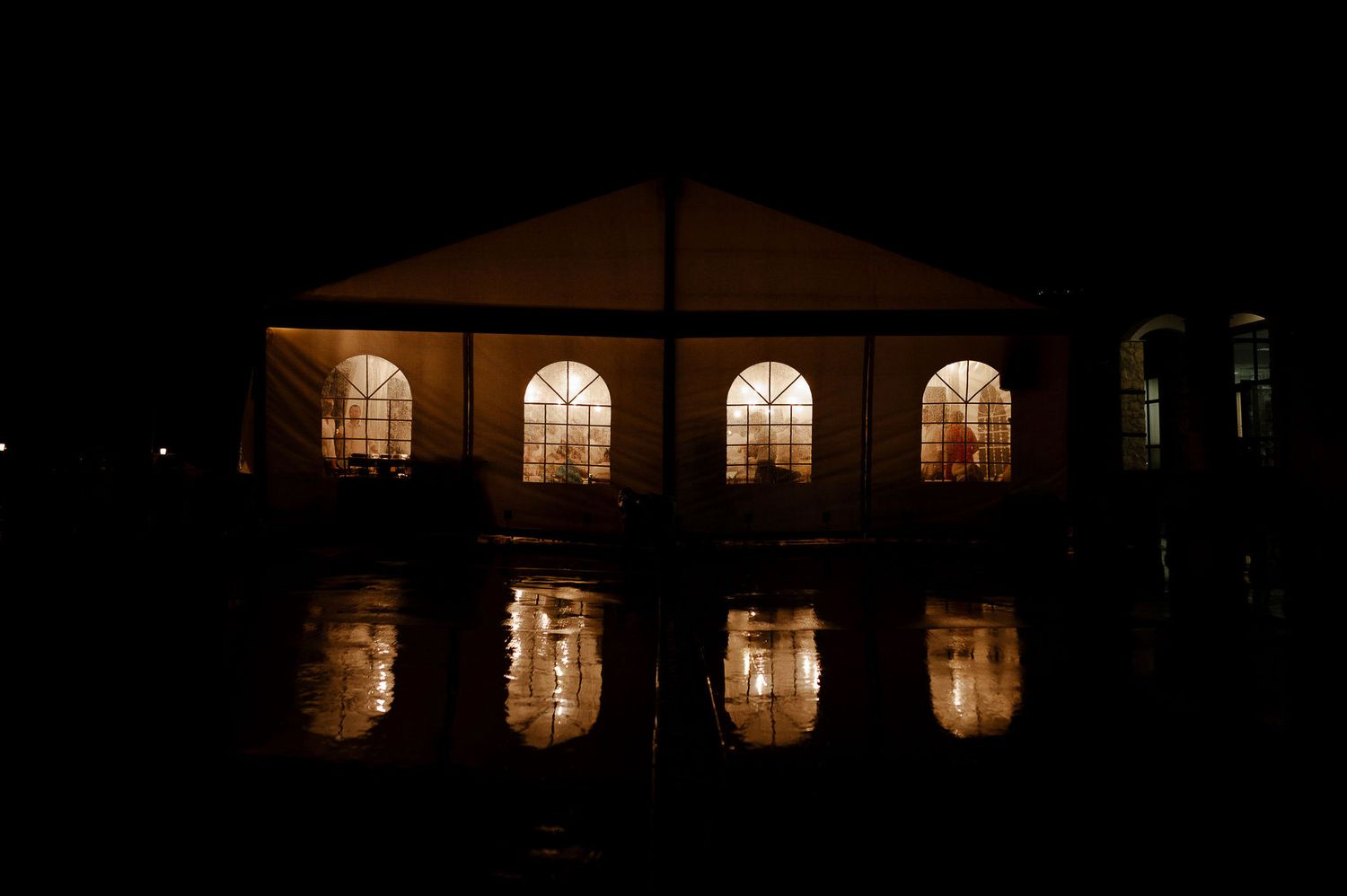 Illuminated arched windows of a venue glowing warmly against the night sky.