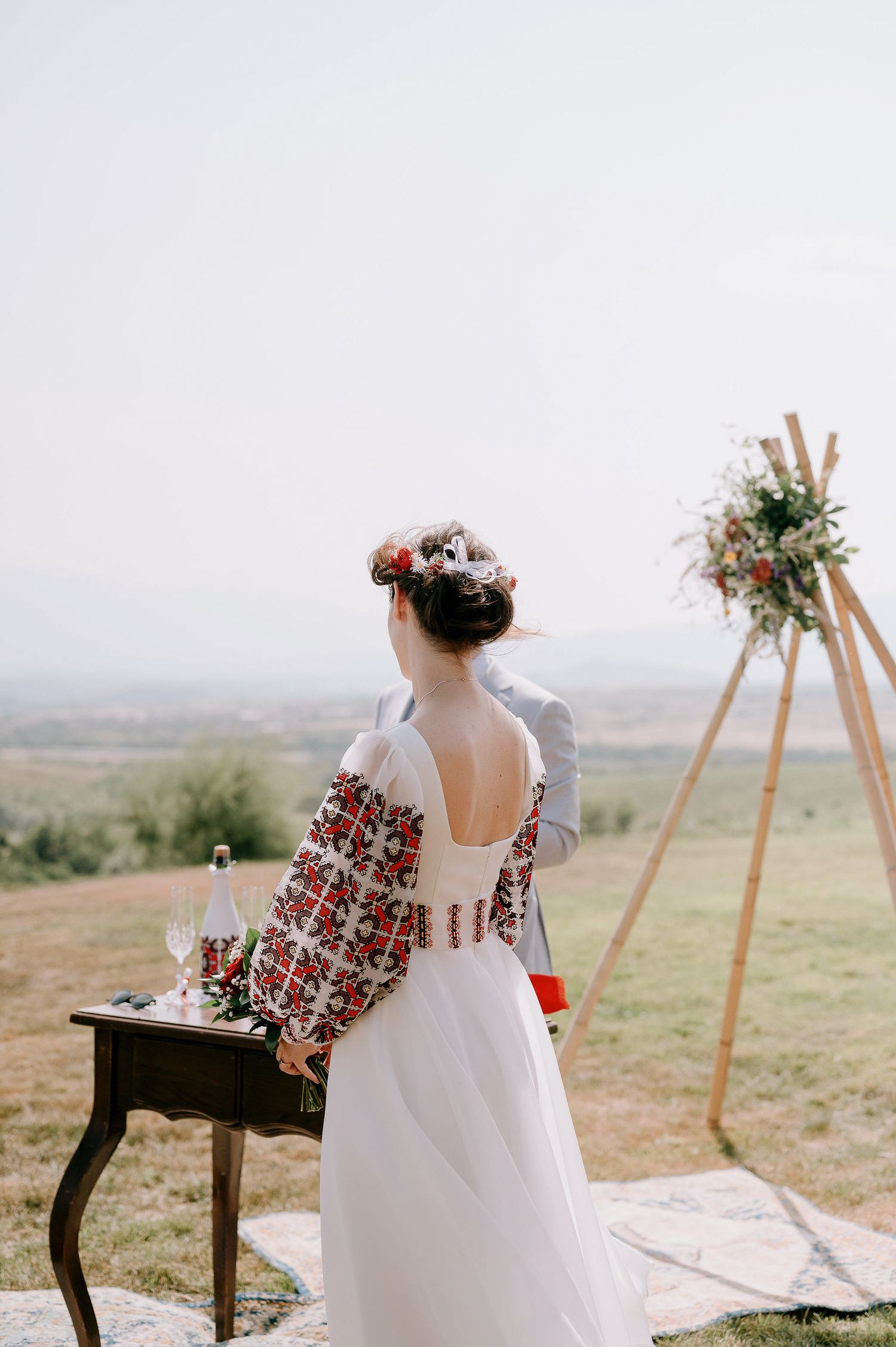 Wedding ceremony setup with wooden arch and rustic table against a scenic mountain backdrop.