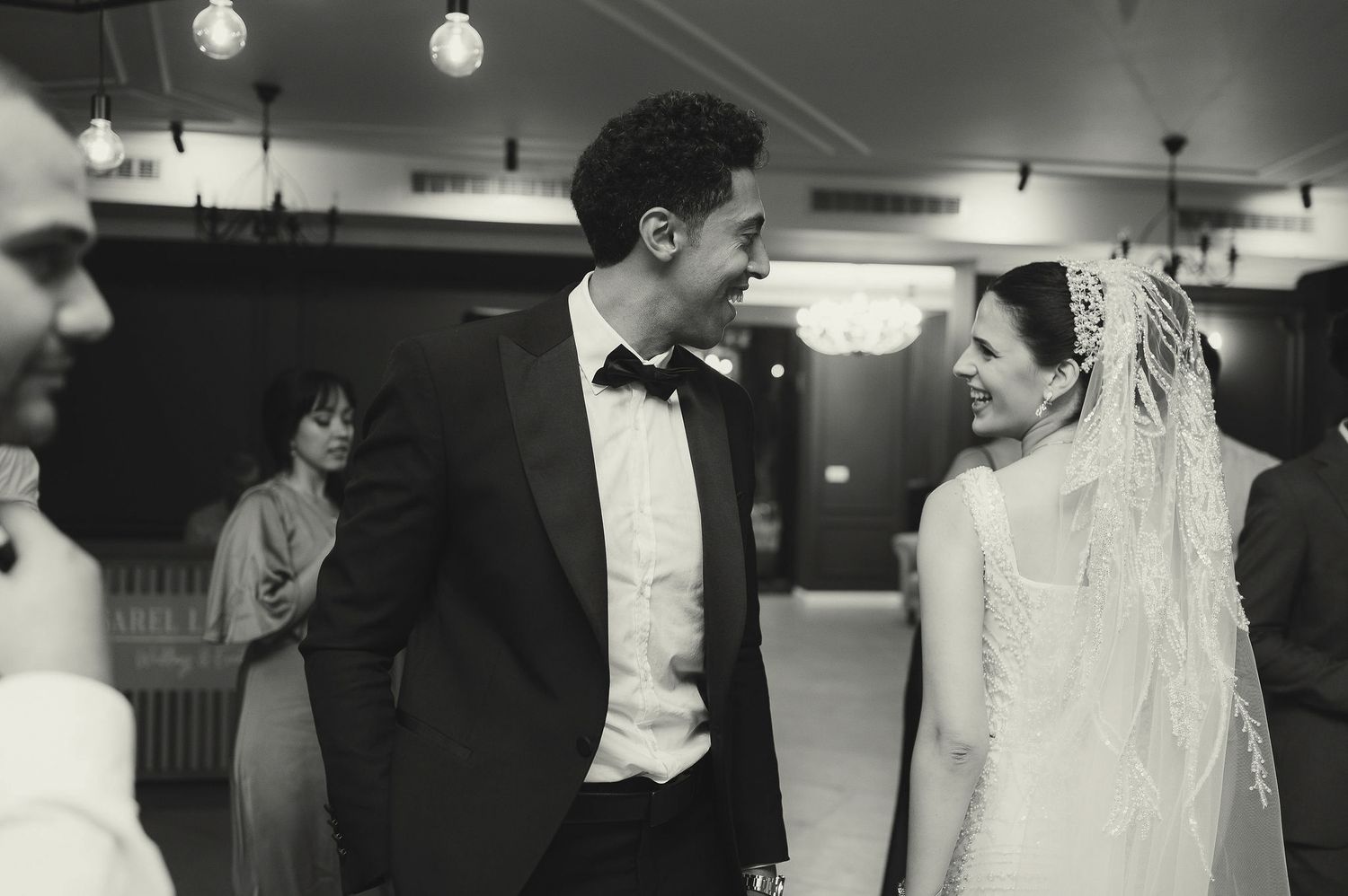 Black and white photo of guests dancing at an indoor celebration.