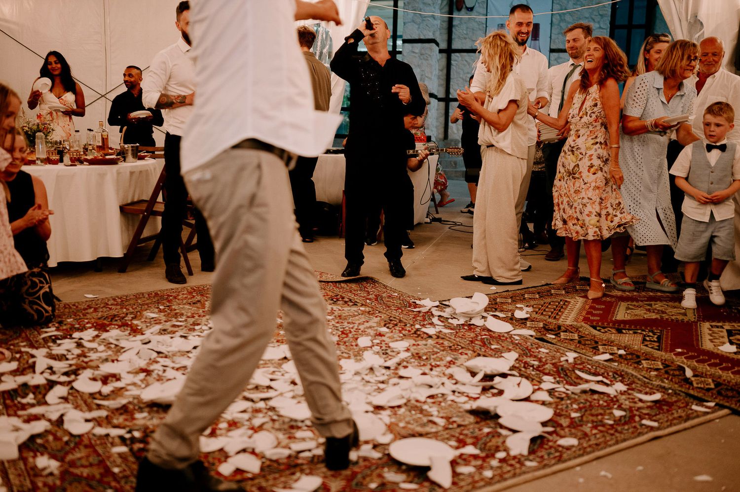 Partygoers dance and celebrate on a floor covered with white confetti at an indoor event.