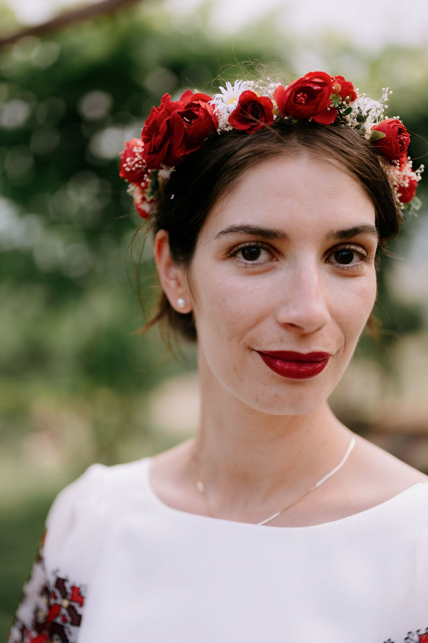 Portrait series showcasing red rose crown and white dress with traditional details.
