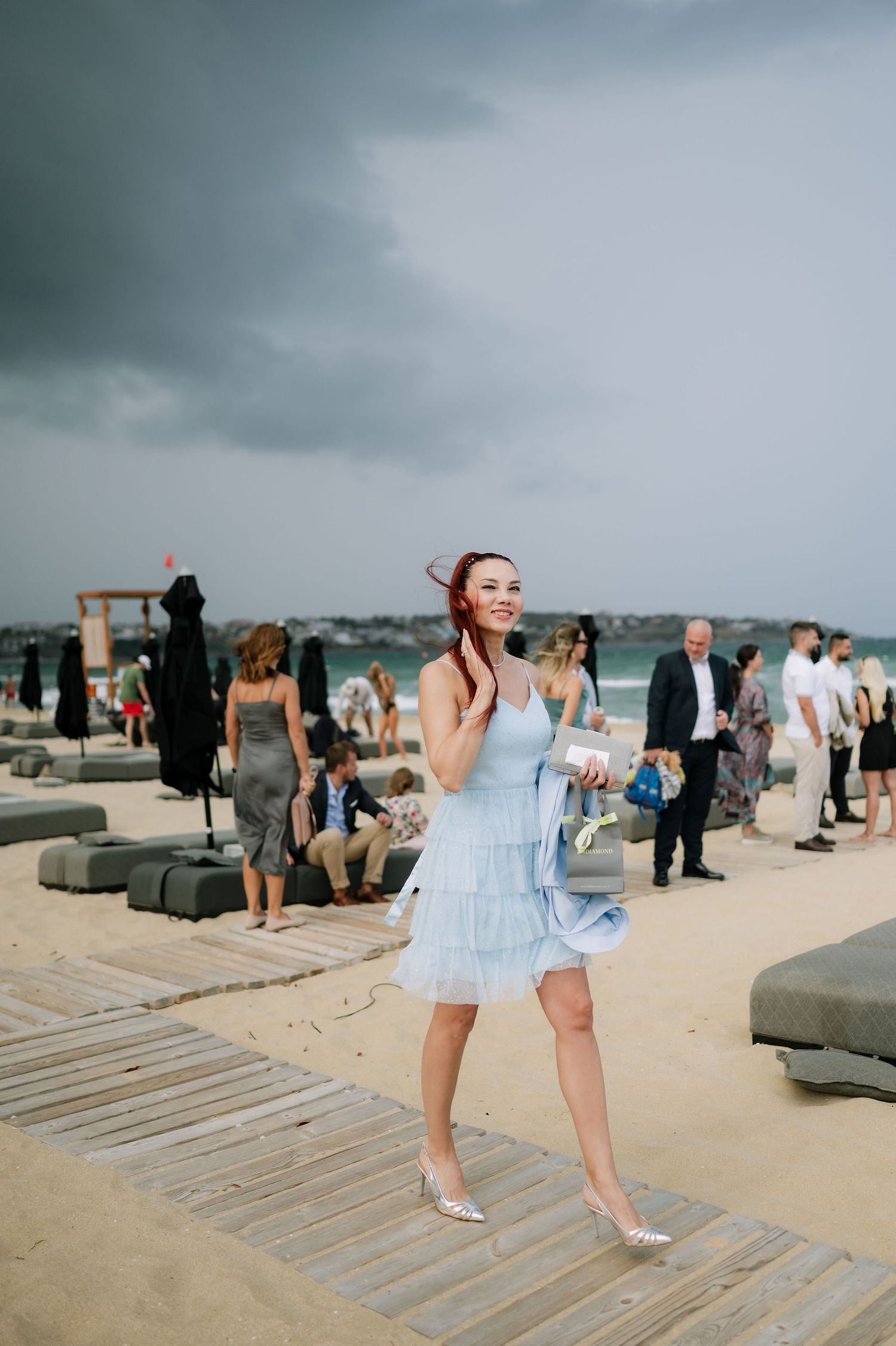 People dancing and celebrating on a wooden boardwalk at the beach.