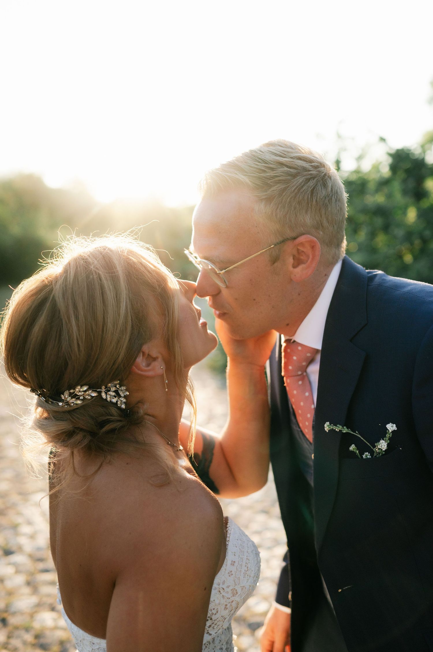 Romantic wedding couple shares an intimate moment in golden sunlight on a beach.