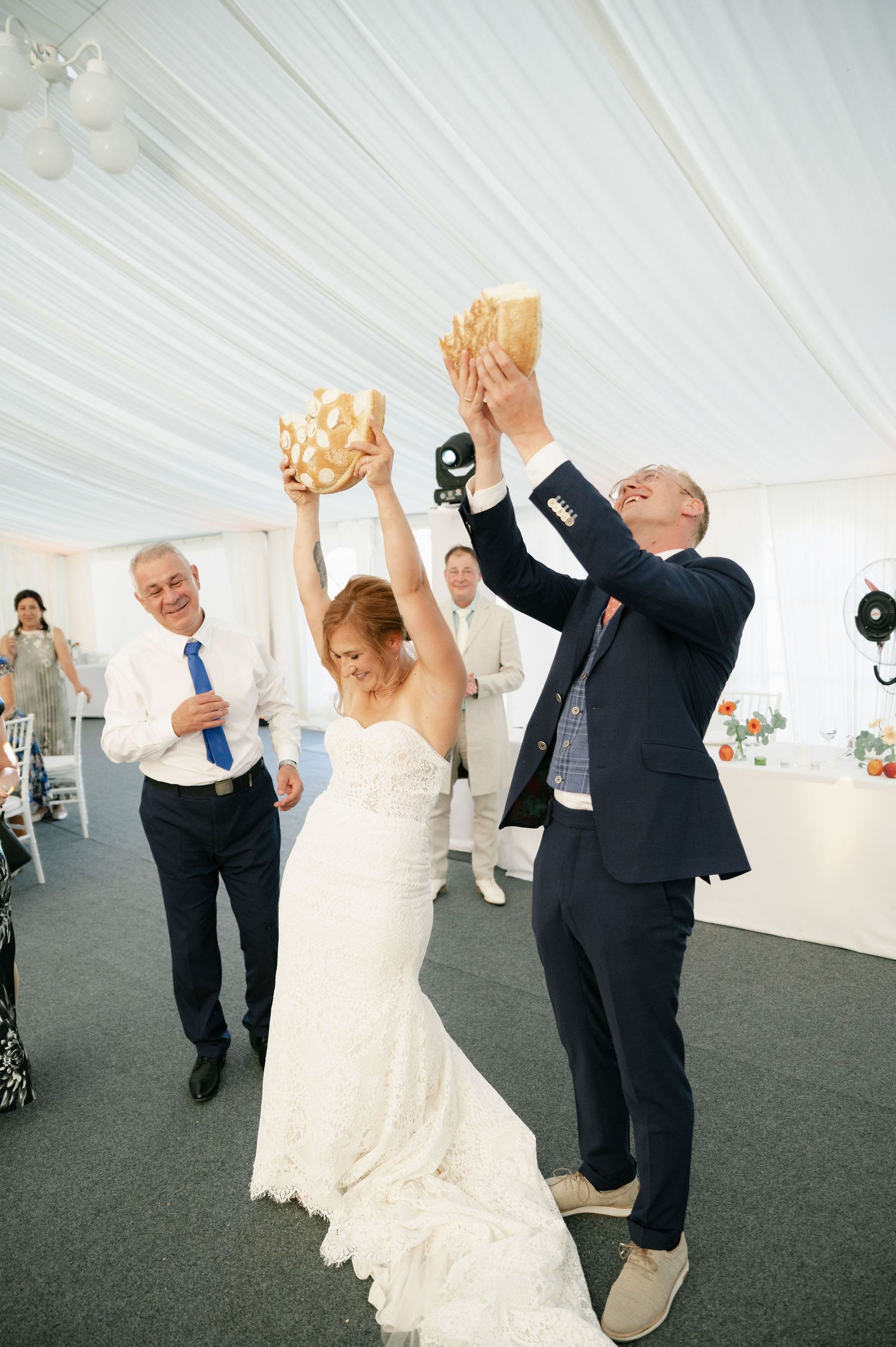 Couples dancing together during a wedding reception in a white tent.