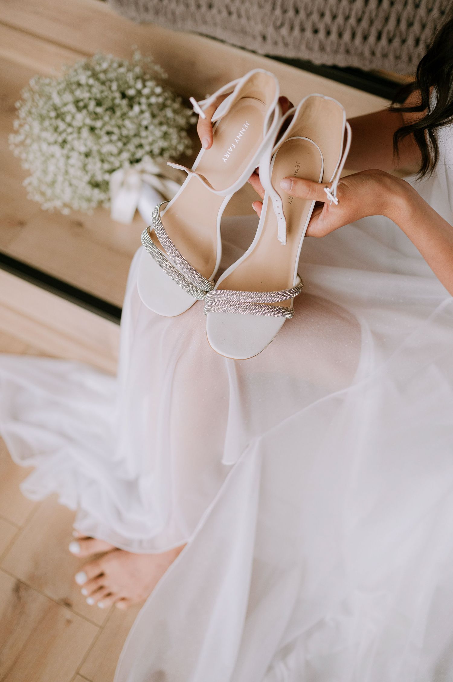 Ivory bridal heels and flowing dress fabric create a romantic wedding detail shot.