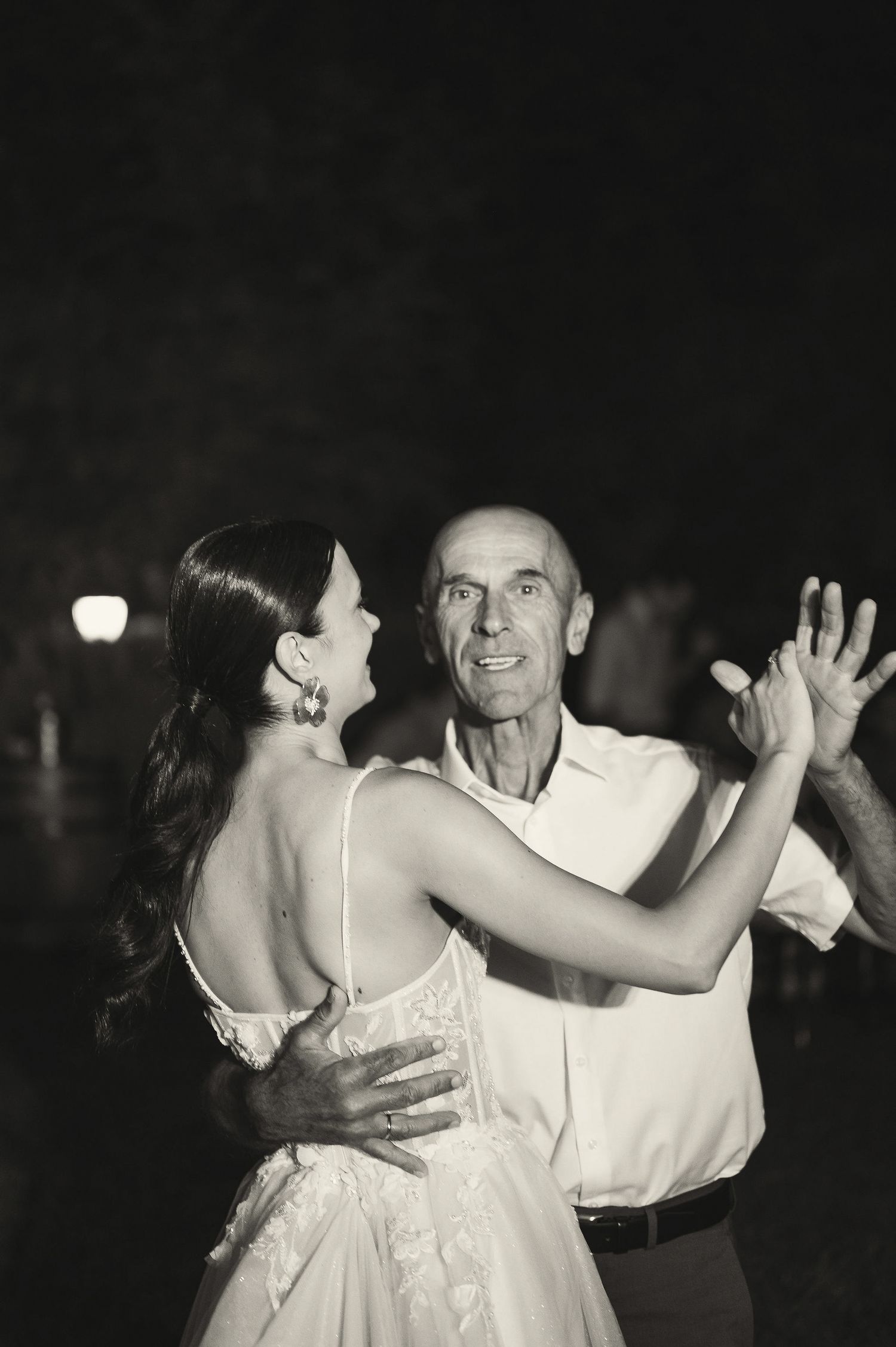 A couple shares an intimate dance moment at their wedding reception under evening lighting.