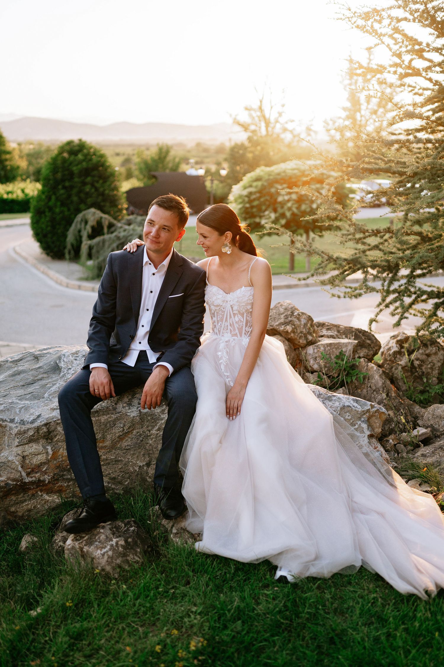Newlyweds share intimate moments while seated on natural rock formations at golden hour.