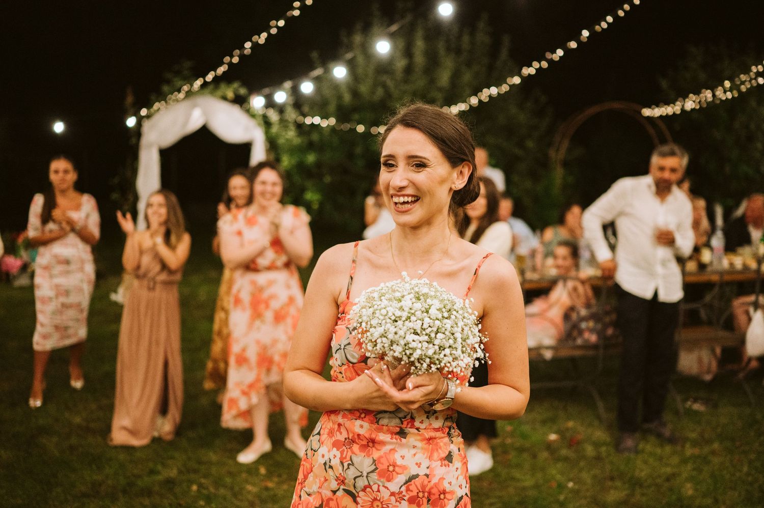 Wedding reception guests dance under twinkling string lights at an outdoor evening celebration.