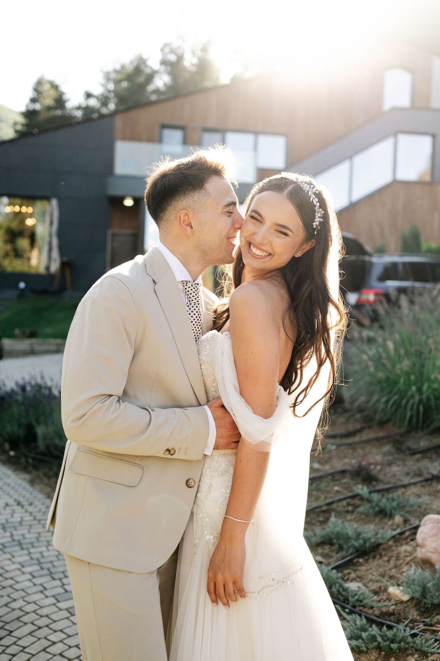 Romantic sunset wedding portrait with couple embracing on stone patio.