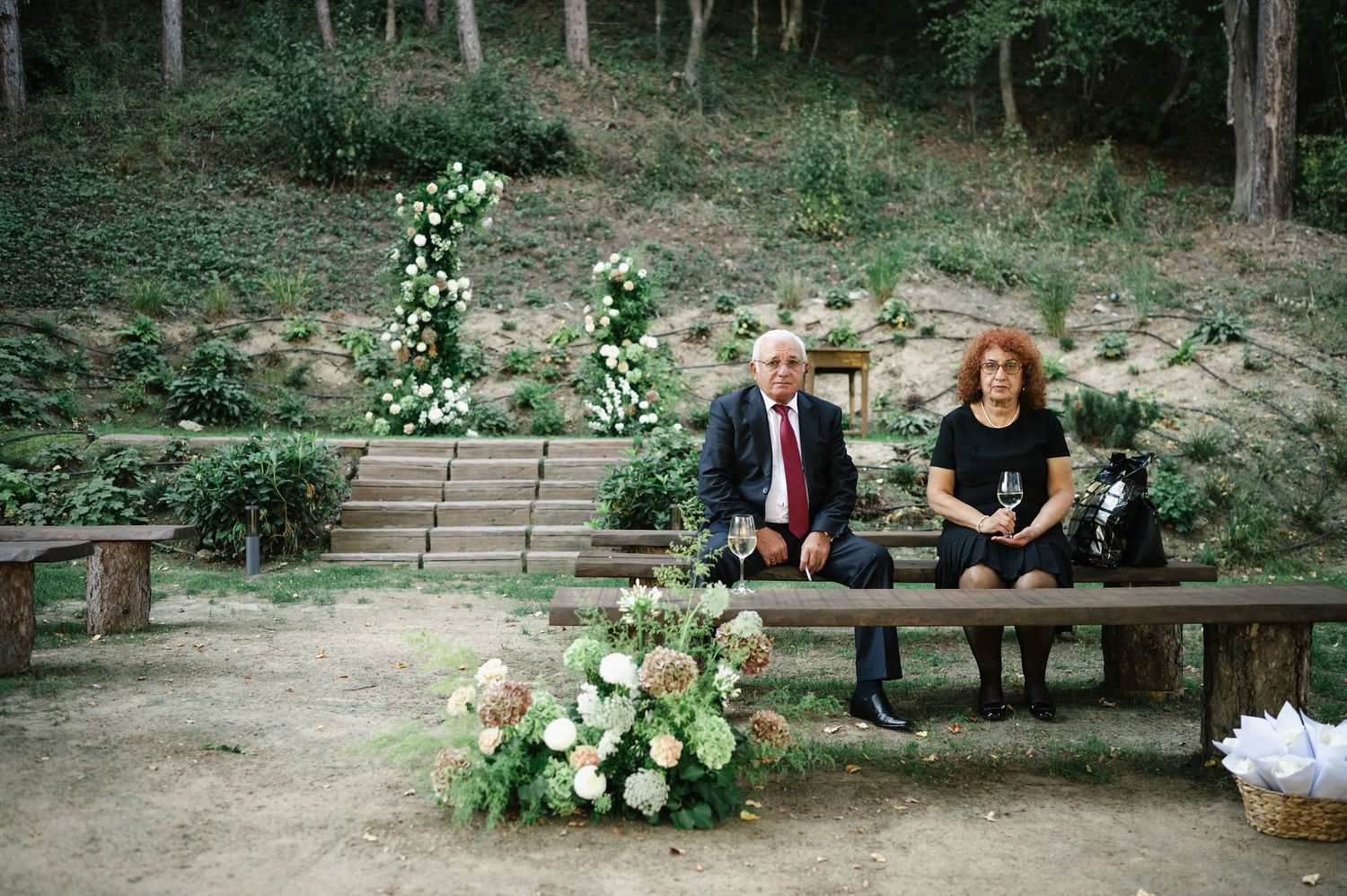 Outdoor wedding venue decorated with floral arrangements and wooden benches.