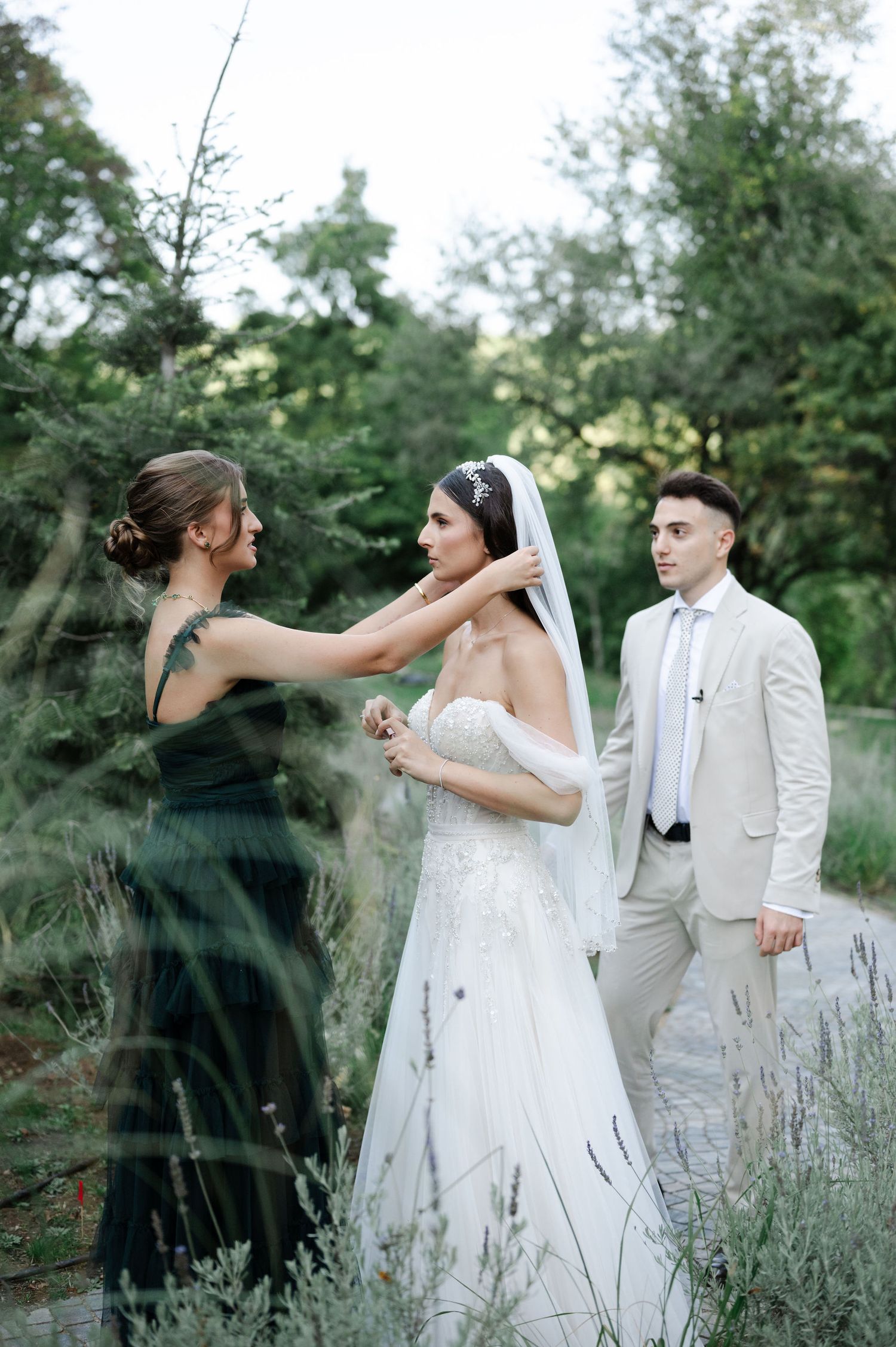Candid wedding party interaction captured in natural outdoor setting with lavender plants.