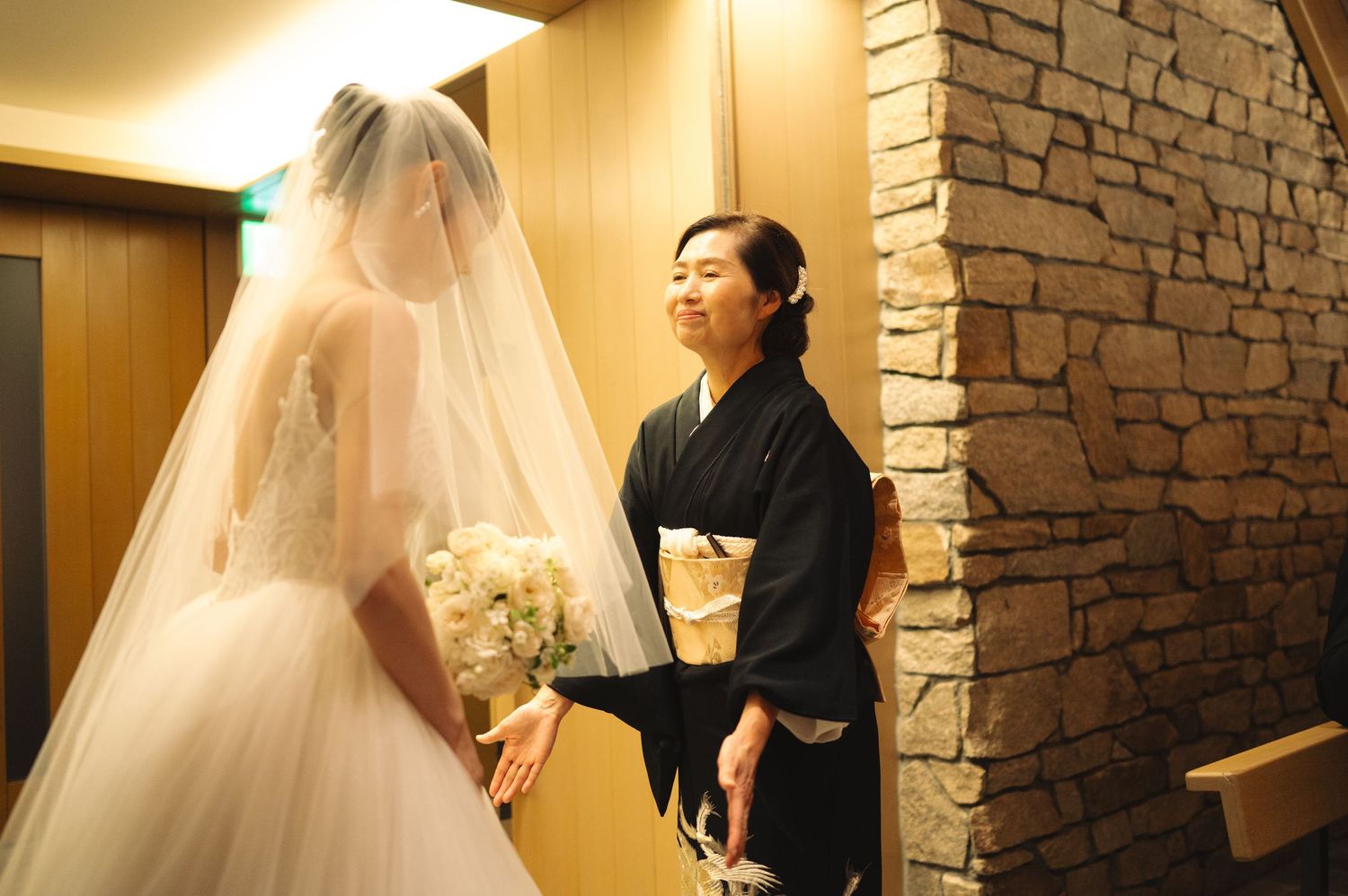 Wedding dress styling session in warmly lit room with stone accent wall.