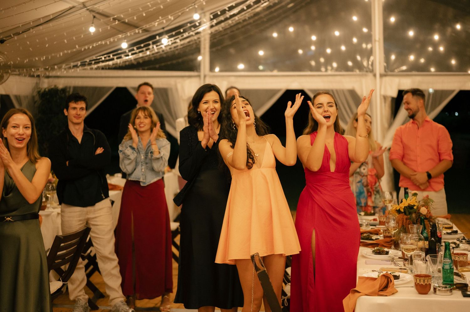 A collage of candid party photos showing guests mingling and dining at an indoor celebration with string lights overhead.