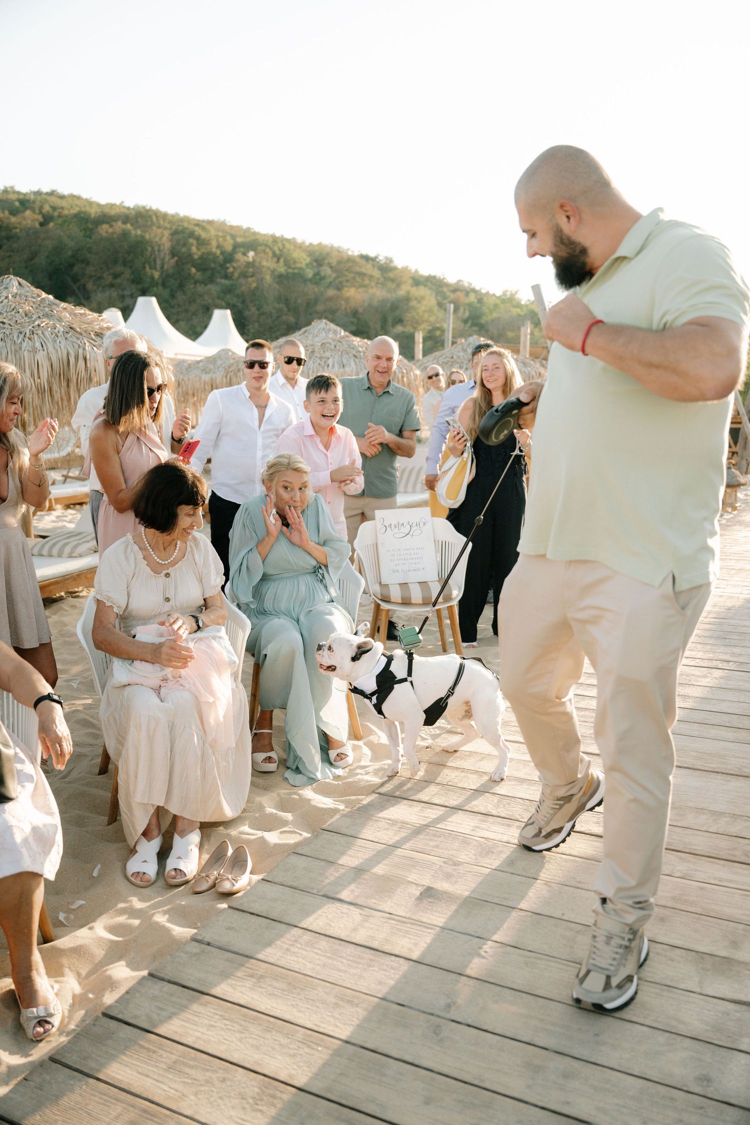 Wedding guests dance together on a wooden deck during sunset at an outdoor celebration.