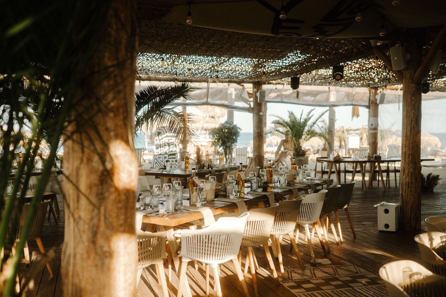 Rustic wedding reception venue with hanging string lights and greenery decorations creating a warm, intimate atmosphere.