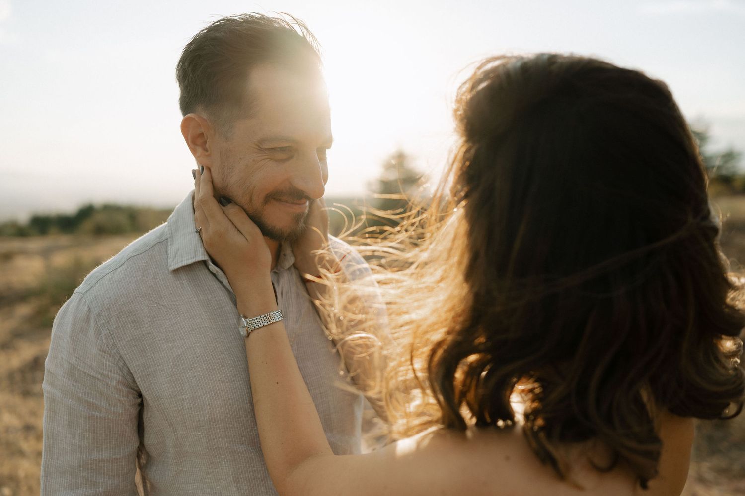 A couple shares intimate moments during a golden hour photoshoot in a scenic outdoor setting.