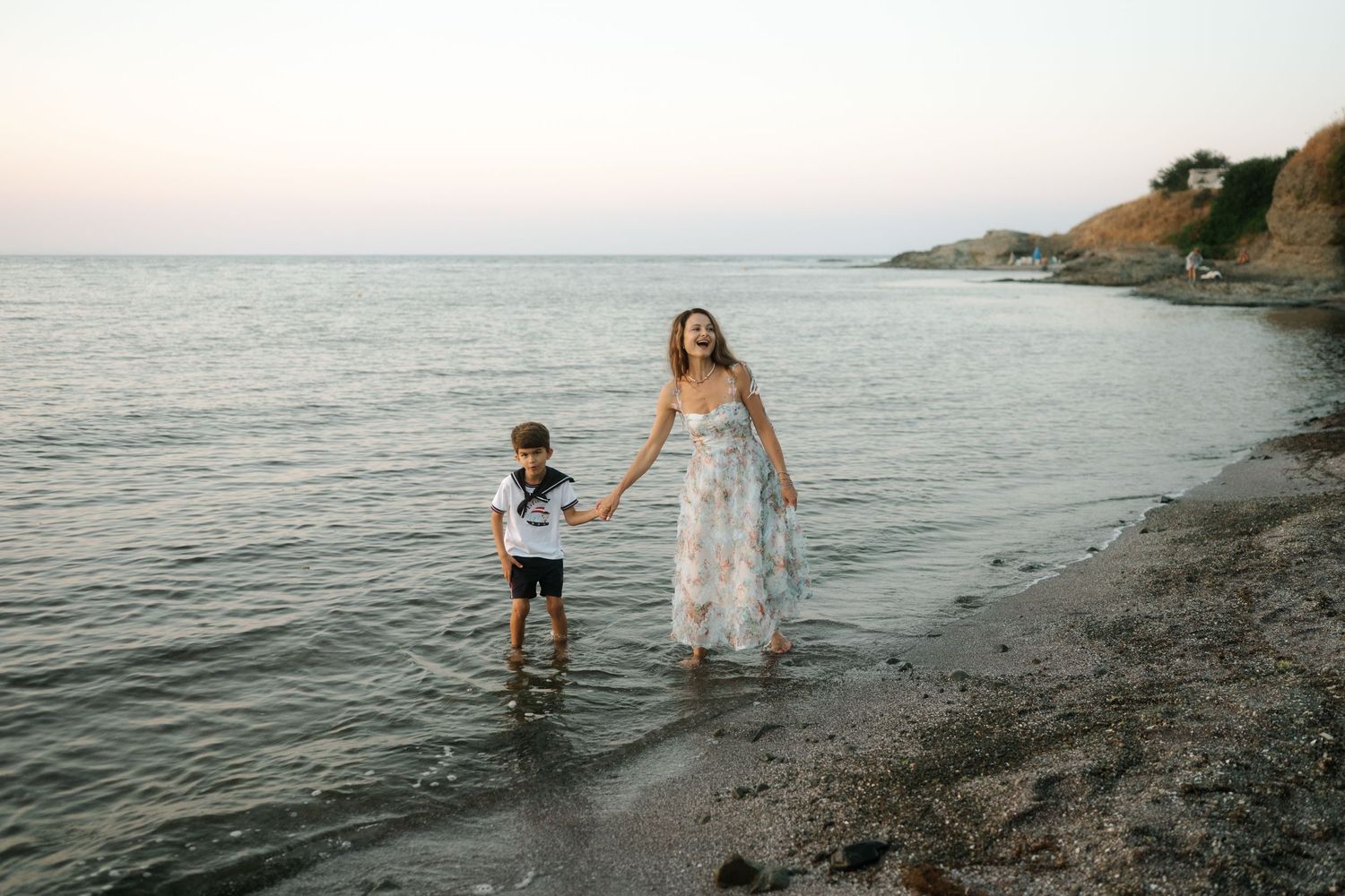 A scenic coastal photoshoot at sunset captures candid moments along the rocky beach shore.