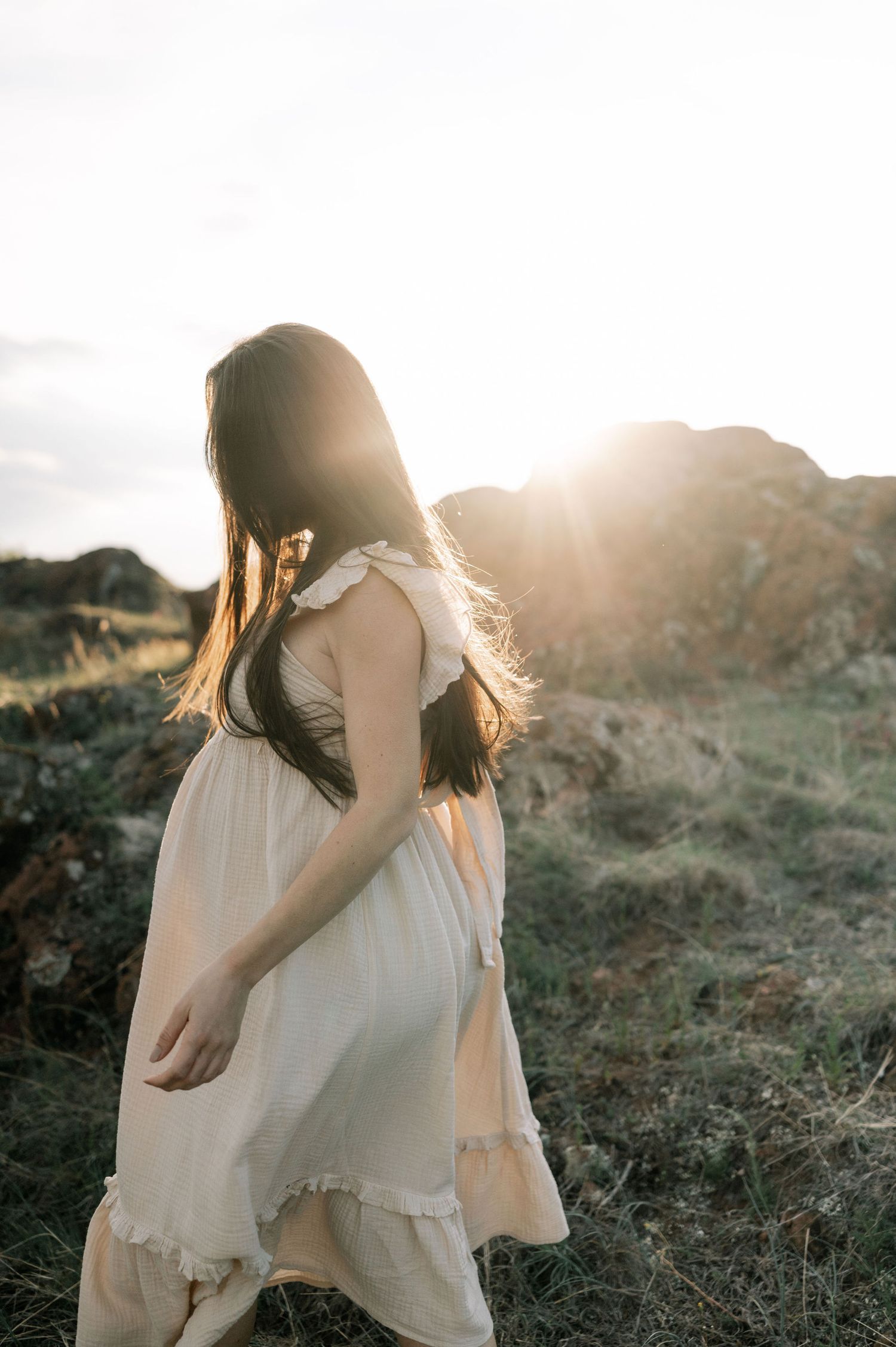 A person in a white flowing dress twirls gracefully in a sunlit field during golden hour.