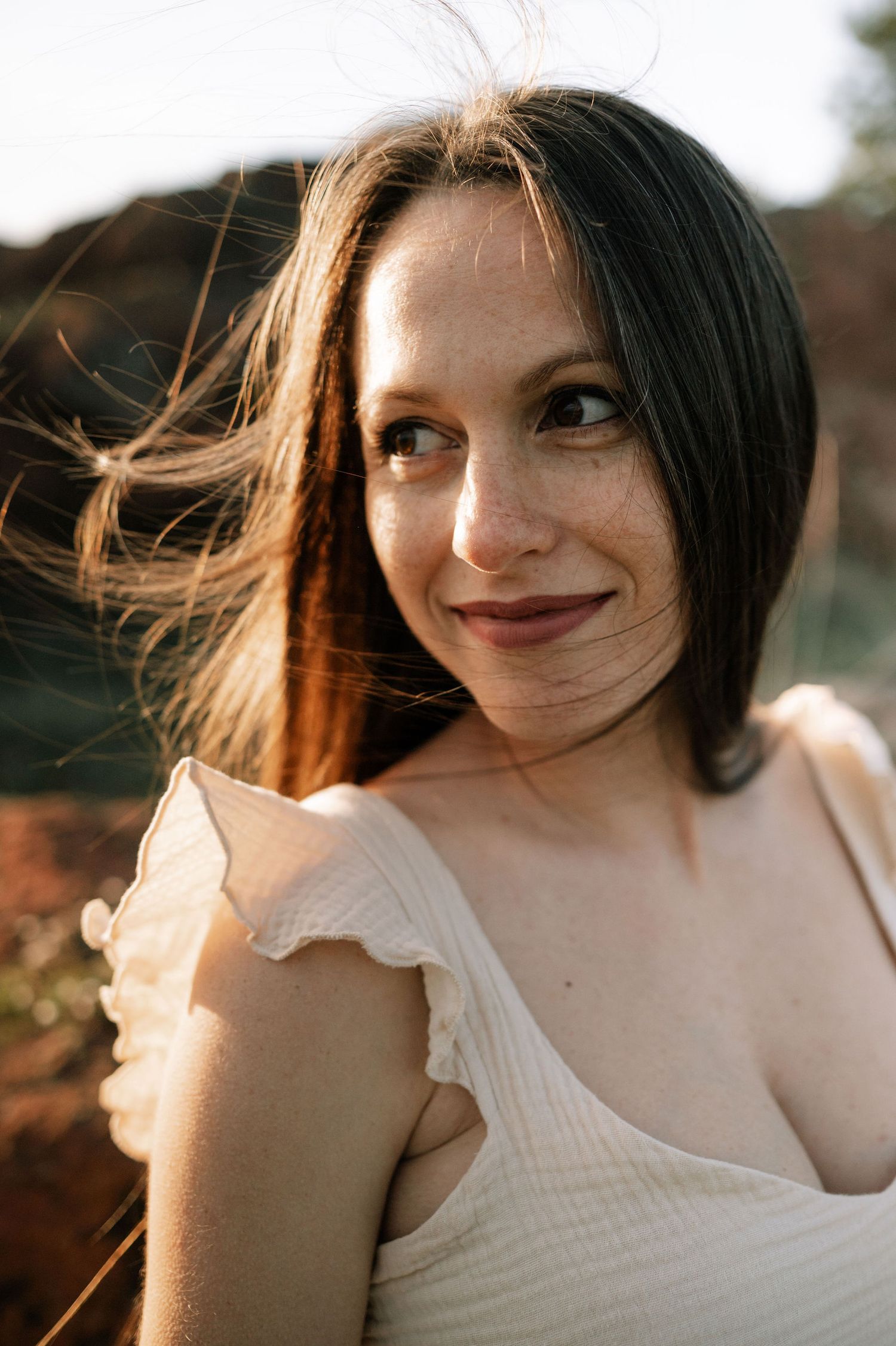 A series of warm-lit portraits showing a person in a white top with windswept hair against a natural outdoor setting.