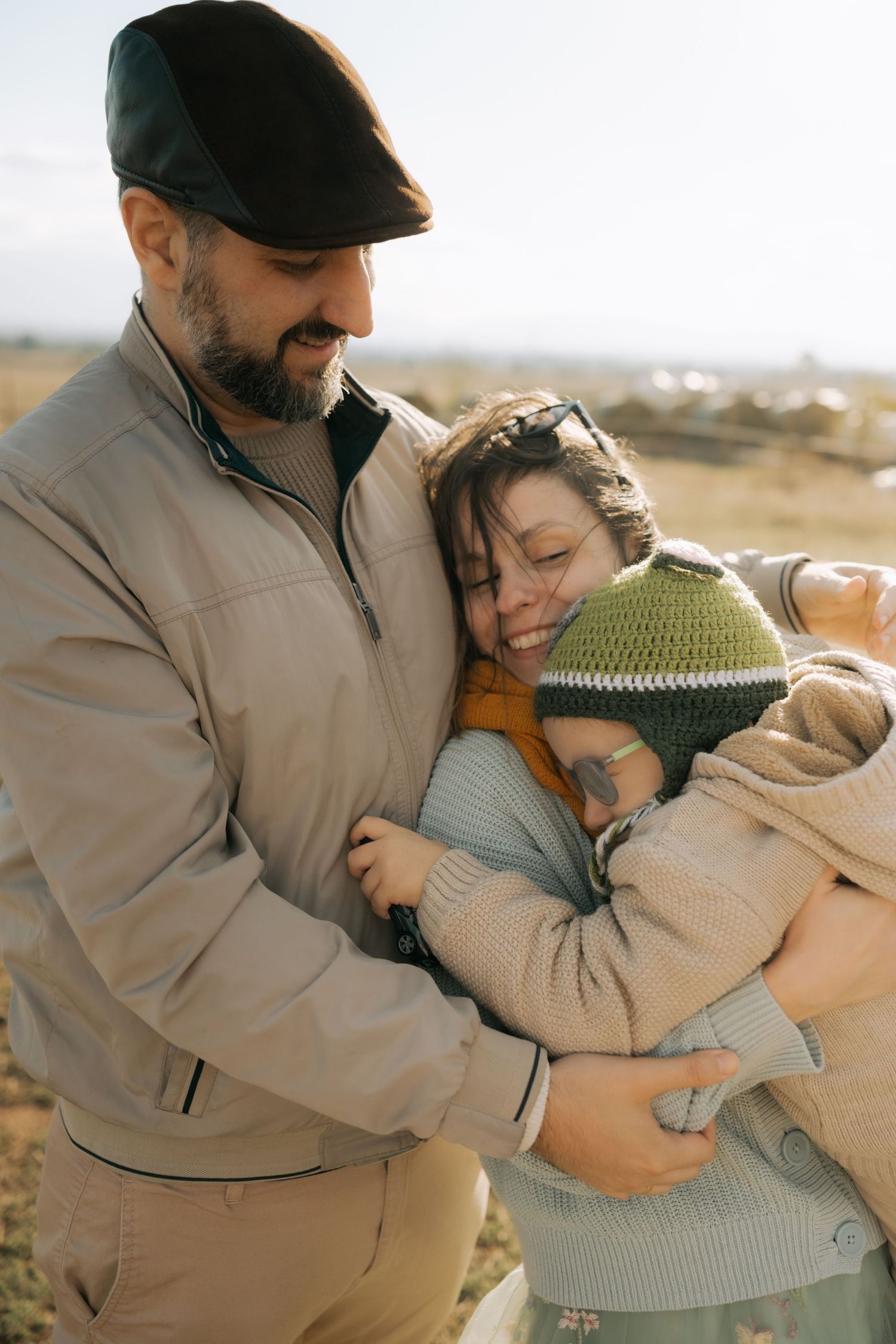 A tender embrace between two people wearing warm sweaters against an outdoor autumn backdrop.